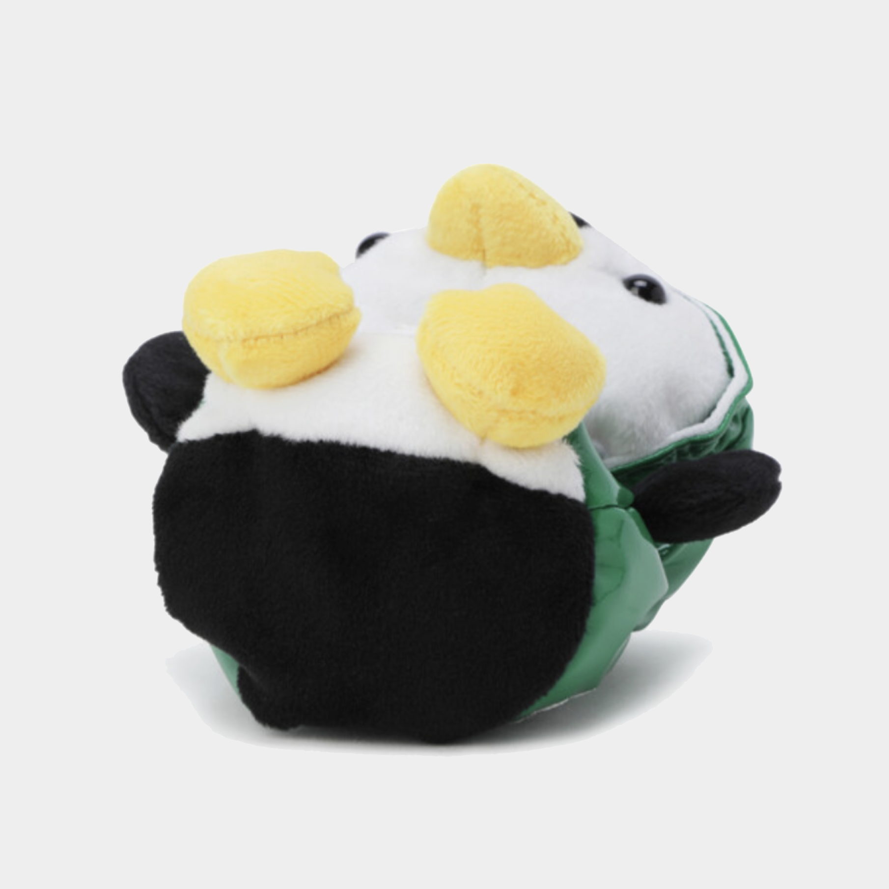 A plush toy shaped like a penguin wearing a green jacket, with black and white body sections and two yellow fluffy accents on top, photographed on a light gray background.