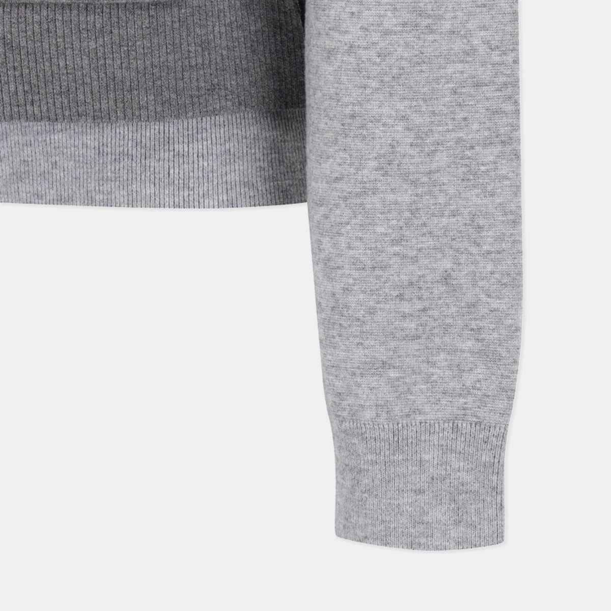 Close-up detail of a light gray heather knit garment, showing the sleeve cuff and ribbed trim against a plain light background.