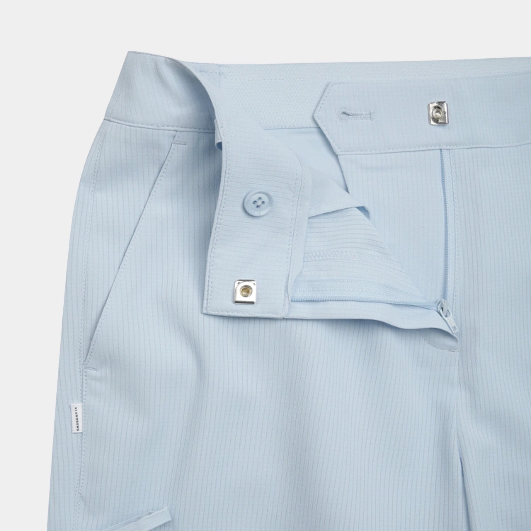 Close-up of light blue pinstriped trousers showing the waistband, button fly, and belt loops against a light gray background.