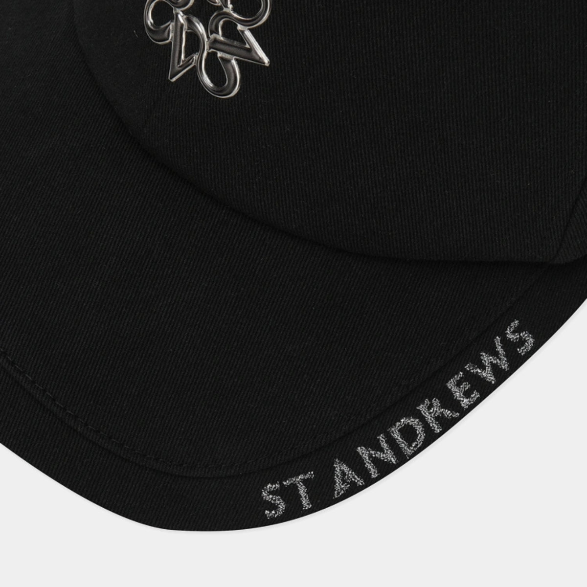 Close-up of a black baseball cap showing a silver metallic St Andrews logo on the front and 'ST ANDREWS' embroidered in silver on the brim, set against a light gray background.