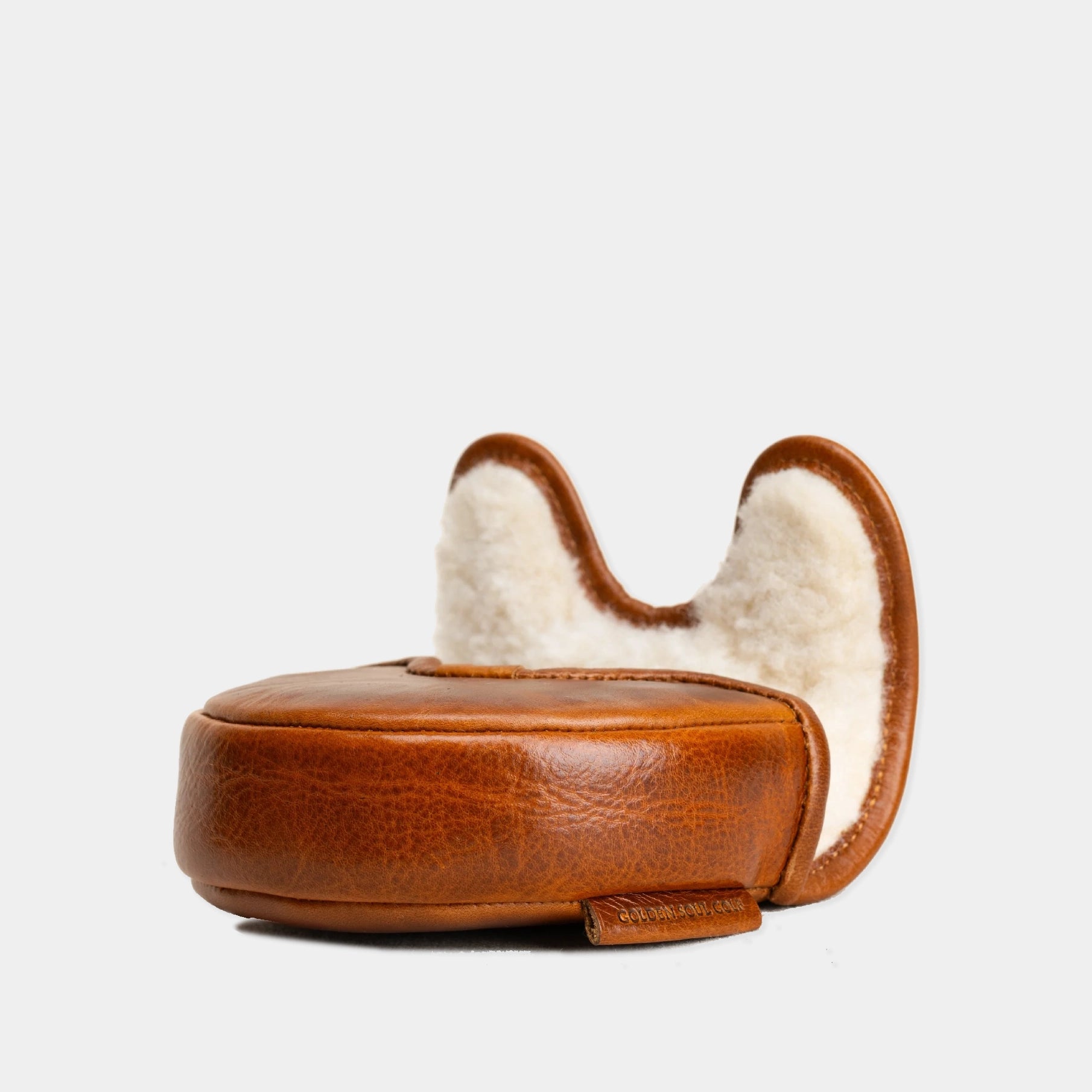 A brown leather OZ1 Putter Cover with a white shearling lining, featuring a rounded base and two upright arching ears, shown against a plain light gray background.