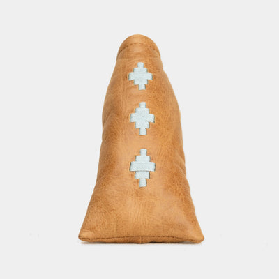 A tan leather blade putter cover with three light blue geometric patterns stitched vertically down the center, shown against a plain light gray background.