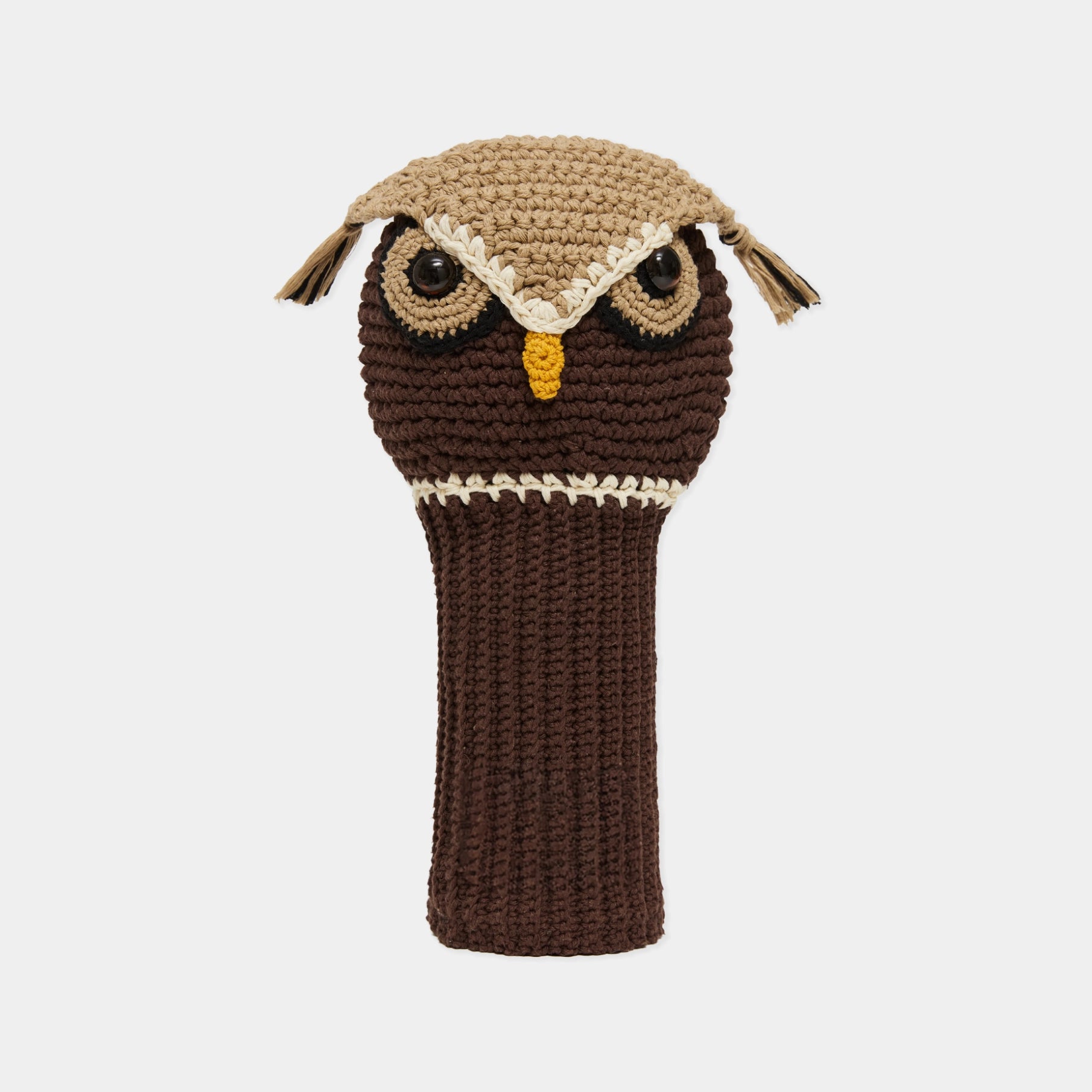 A crocheted owl-shaped golf club headcover in dark brown and tan, featuring embroidered eyes, a yellow beak, and ear tufts, shown against a light gray background.