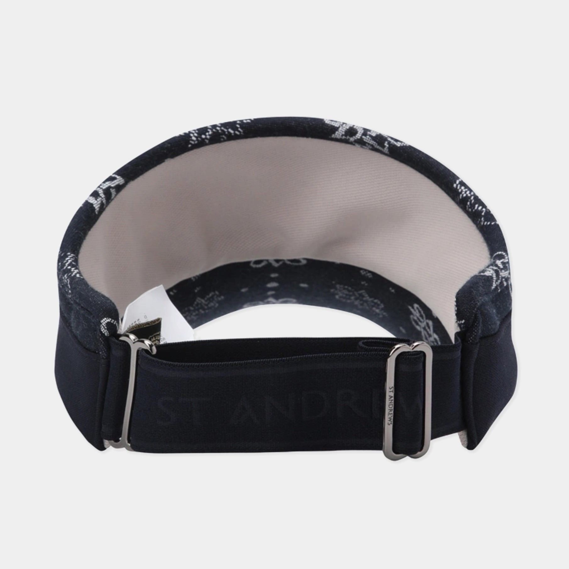 A close-up of a St. Andrews bandage roll, showing the navy blue fabric with white printed cross patterns, a light beige inner lining, and a dark navy adjustable strap with a silver metal buckle.