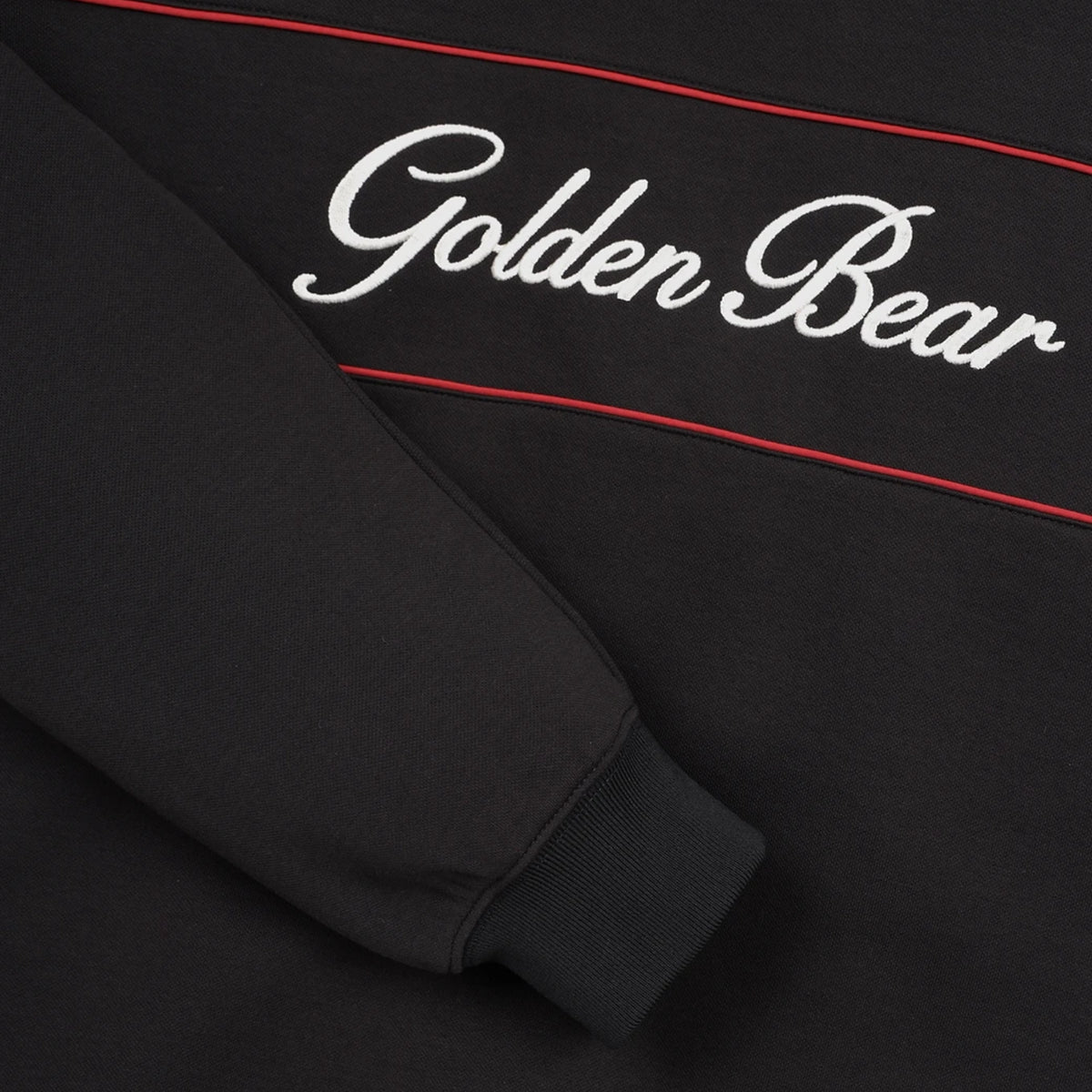Close-up of a black sweatshirt featuring white cursive 'Golden Bear' embroidery and thin red accent lines.