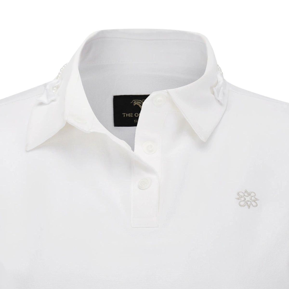 White collared polo shirt with a button placket, decorative lace trim on the collar, and a small embroidered floral logo on the left chest.