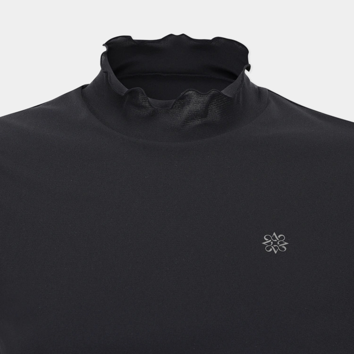 Close-up of a black athletic top with a high mock neck collar and a small silver geometric logo on the left chest, shown against a light gray background.