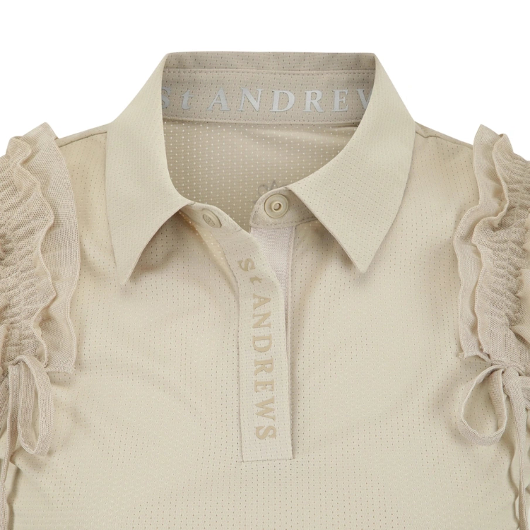 Close-up of a cream-colored St Andrews polo shirt featuring a textured fabric, ruffled sleeve details, and a button-down collar with a branded neck label.