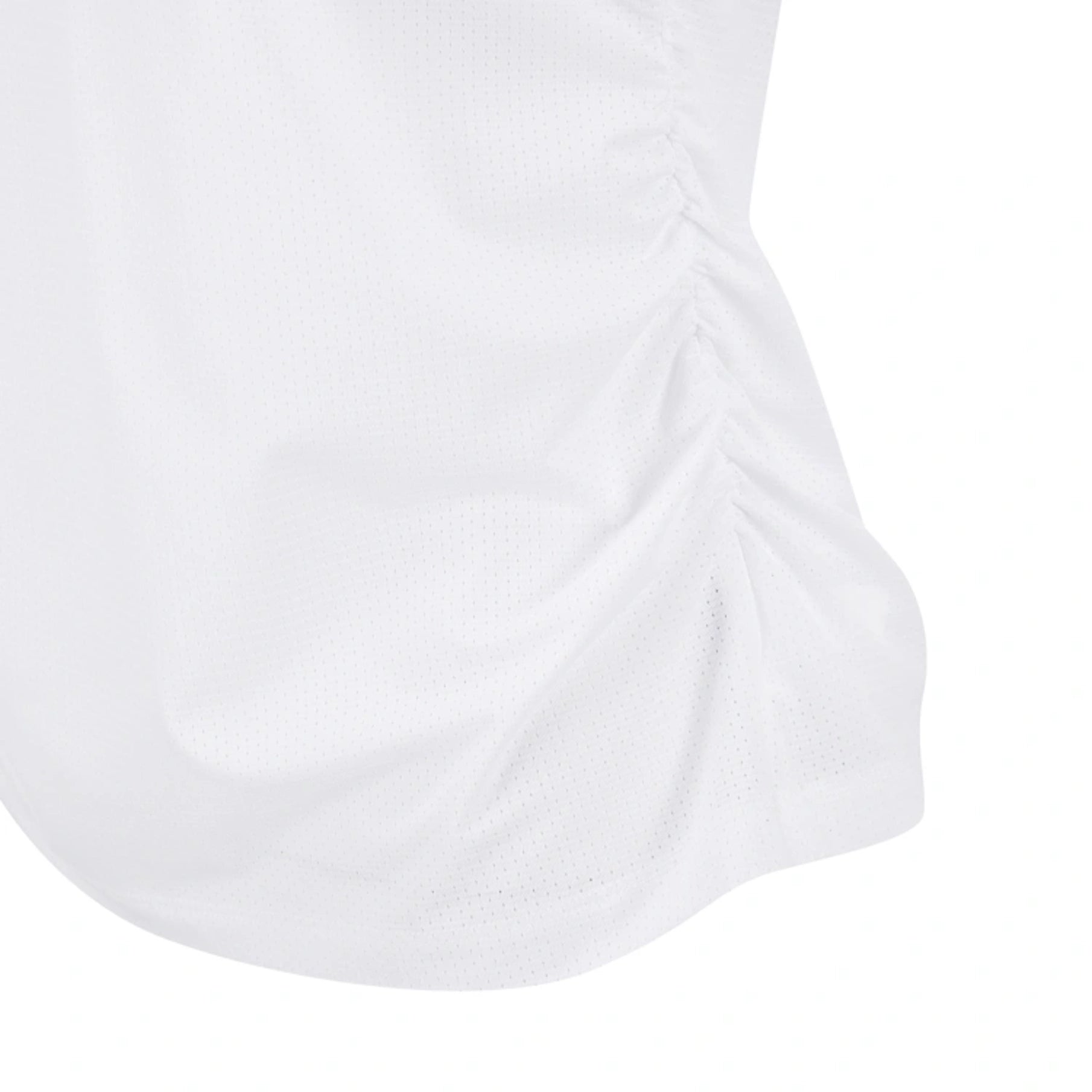 Close-up of a white textured athletic garment with a gathered ruched seam on the side, showing the fabric texture and hem detail against a white background.