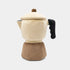 A plush moka pot wood cover with a cream-colored body and lid, a brown base, and a black handle, photographed on a light gray background.