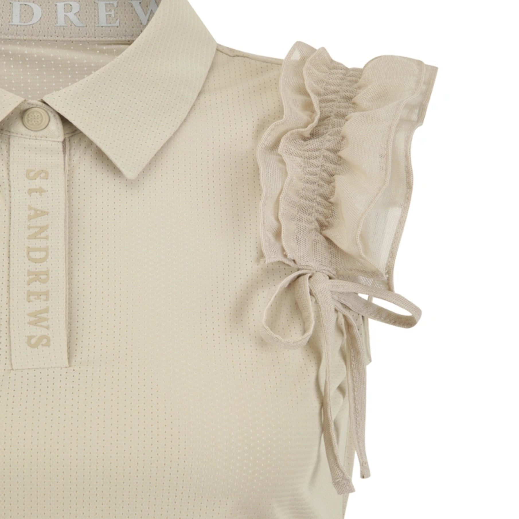 Close-up of a light beige polo shirt with a textured knit fabric, featuring a collar, a button placket with 'ST ANDREWS' printed vertically, and ruffled cap sleeves with side tie details.