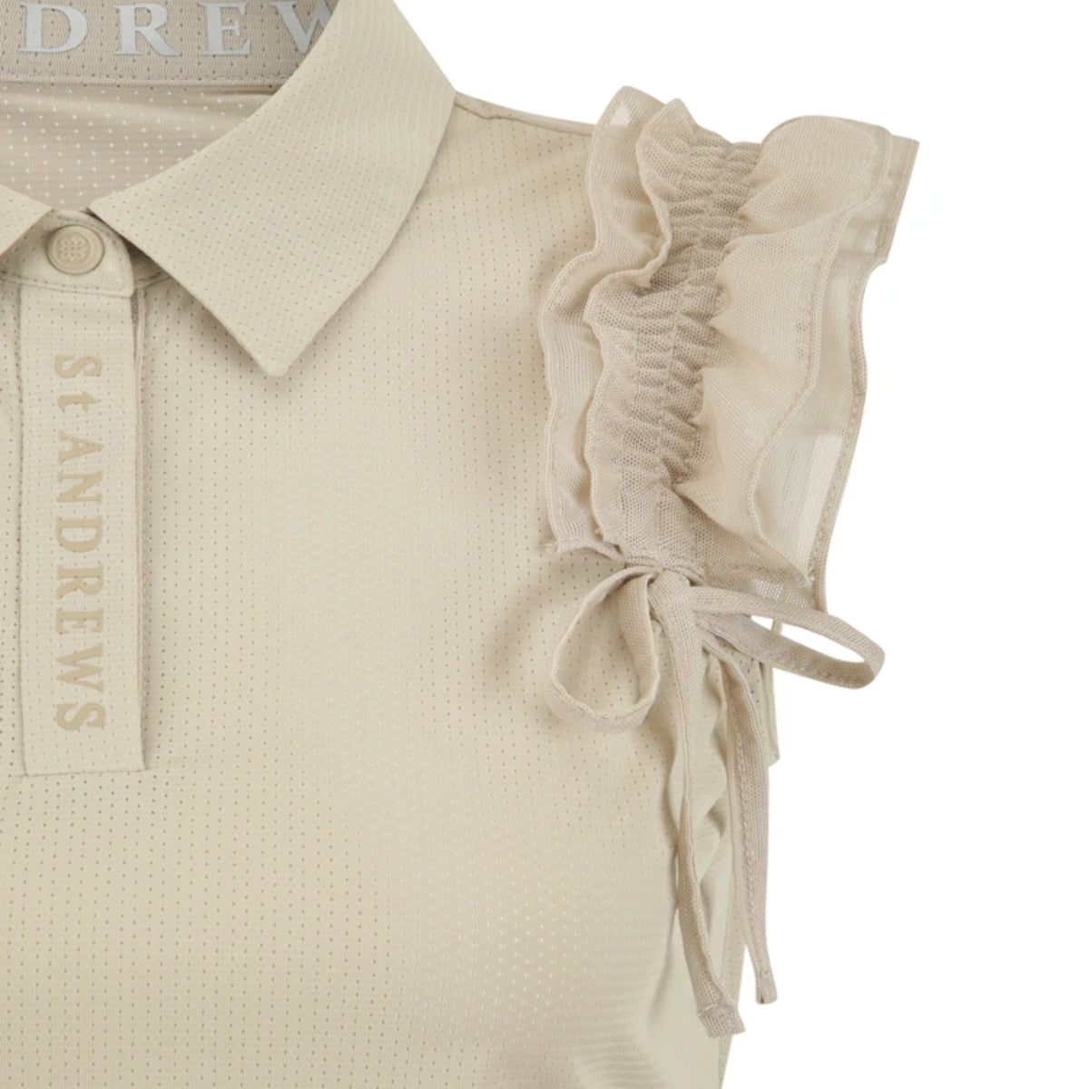 Close-up of a light beige polo shirt with a textured knit fabric, featuring a collar, a button placket with 'ST ANDREWS' printed vertically, and ruffled cap sleeves with side tie details.