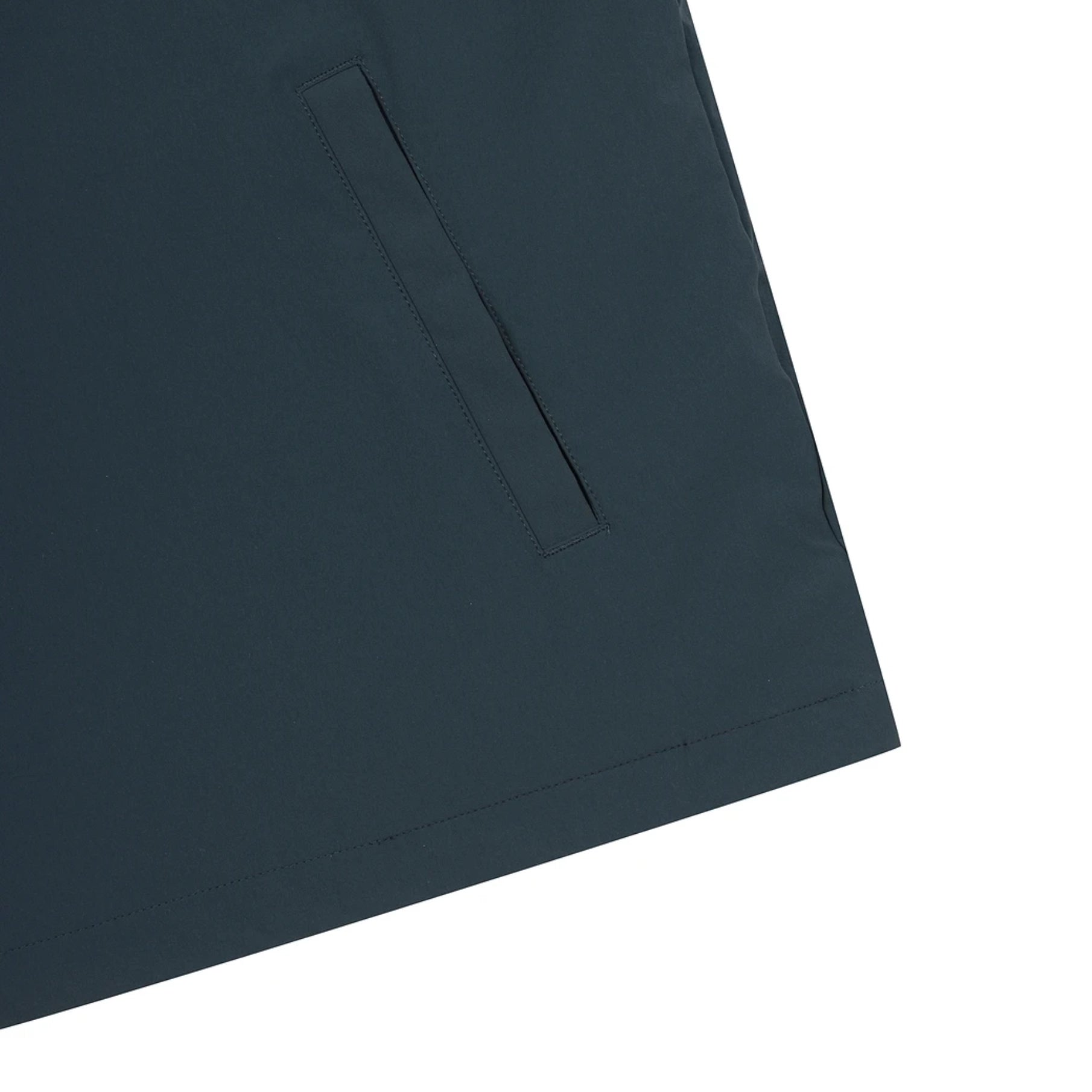 Close-up of a dark navy blue garment corner showing a stitched pocket tab and hem against a white background.