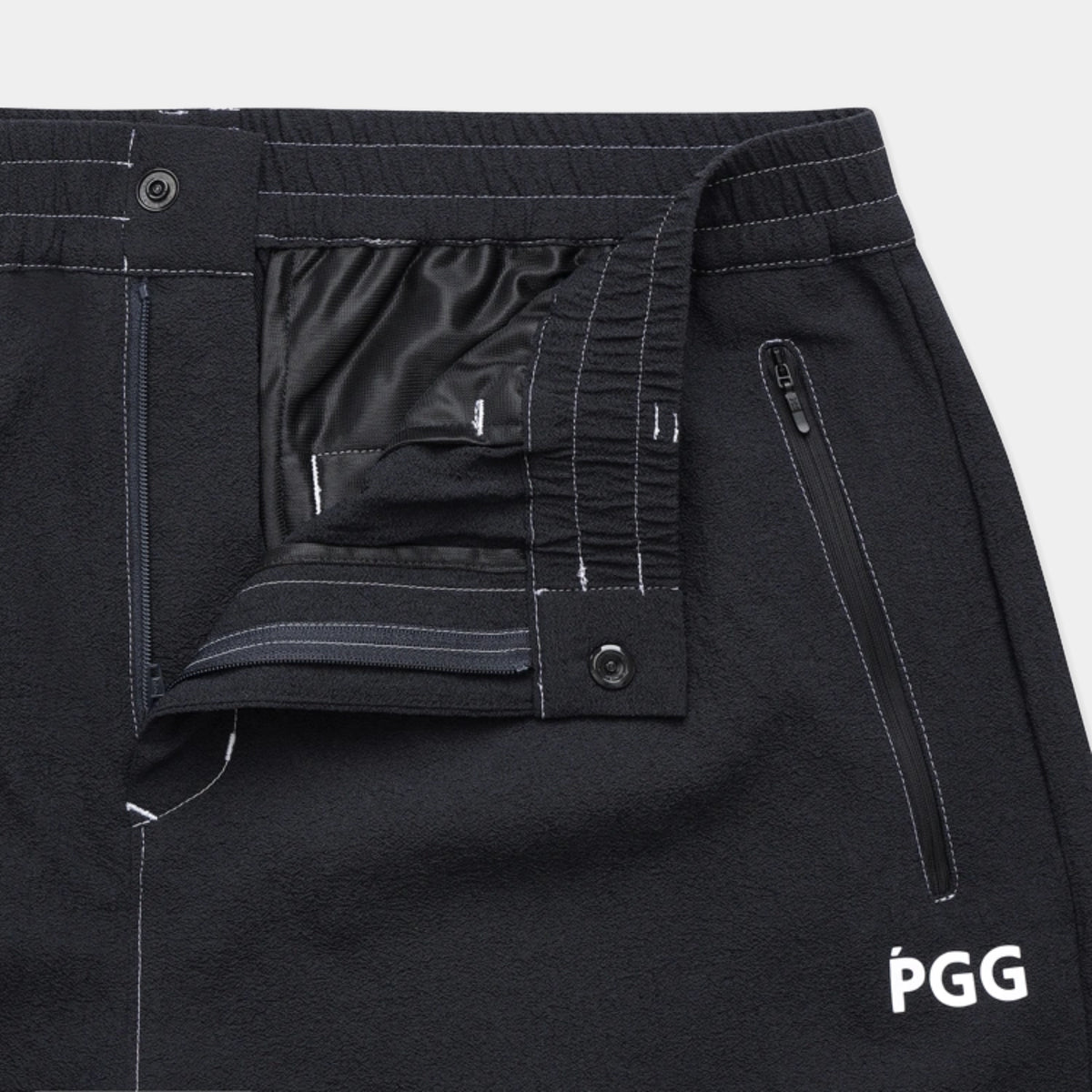 Close-up of black PGG athletic pants showing the interior waistband, elasticized front closure, zippered pocket, and white PGG logo on the lower right leg.