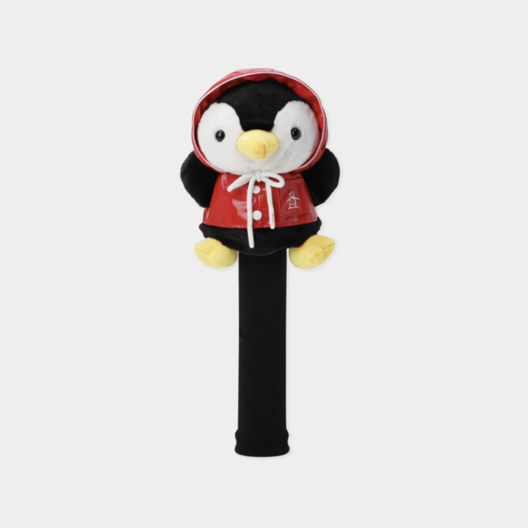 A plush penguin headcover on a black golf club shaft, dressed in a red hooded jacket with white drawstrings and yellow accents, set against a light gray background.