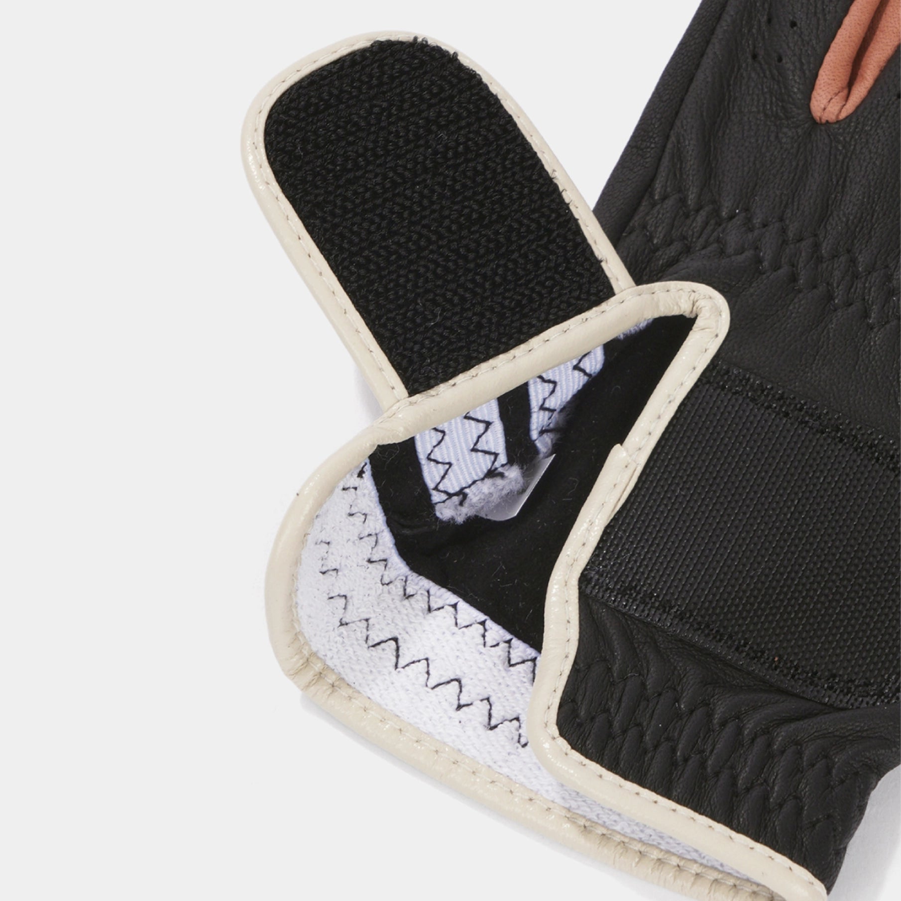 Close-up of a black textured support brace or orthotic with cream-colored stitched borders and a white patterned inner lining, shown against a light gray background.