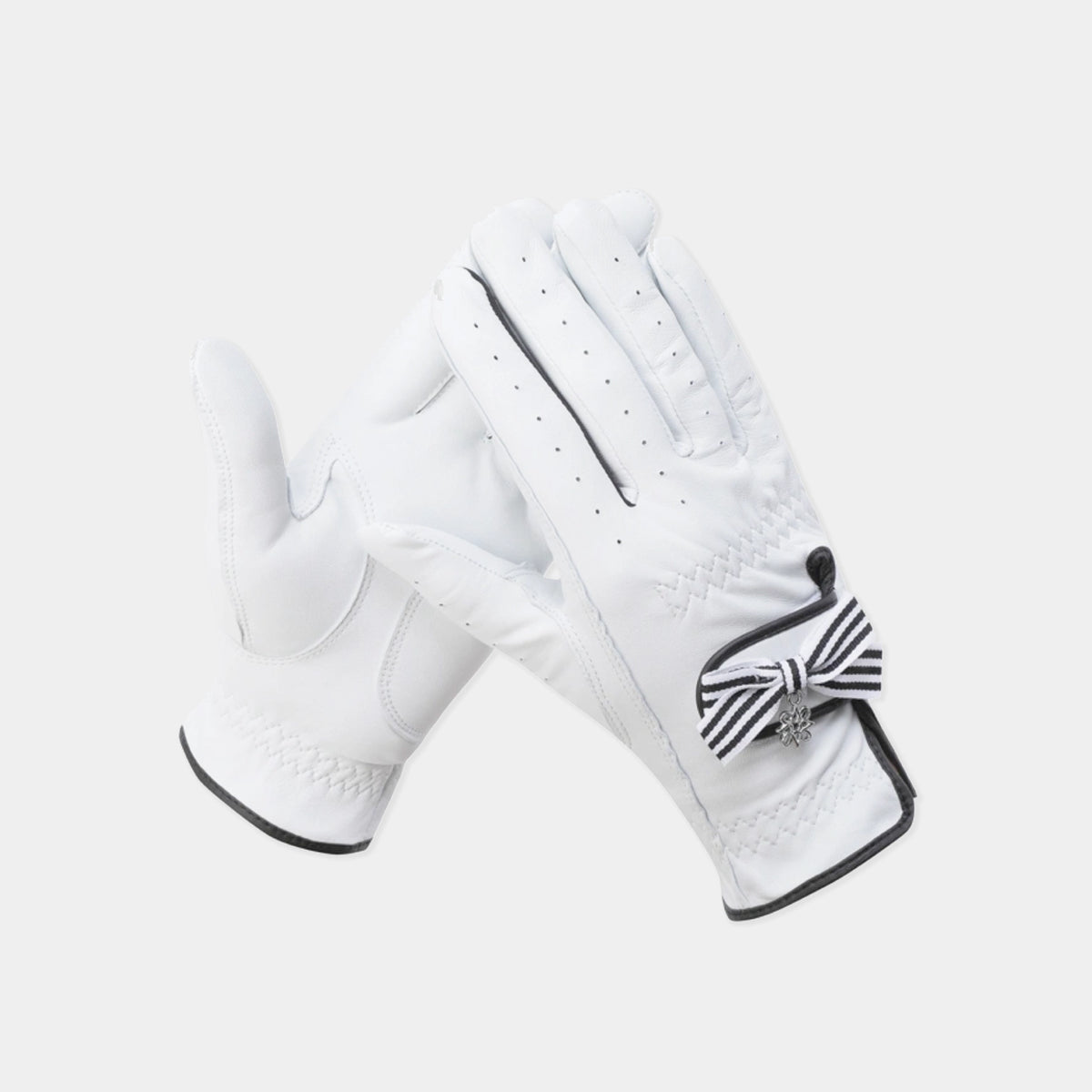 A pair of white leather golf gloves with black trim and a black-and-white striped bow detail on the back of one glove, shown against a light gray background.