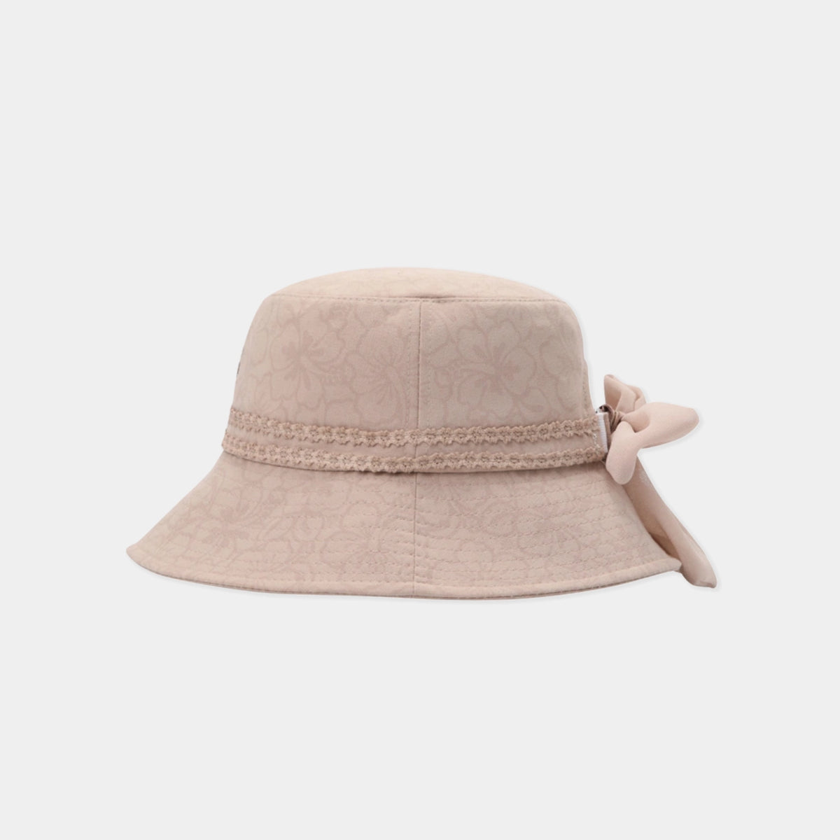 A light beige bucket hat with a subtle floral jacquard pattern, a decorative lace band, and a matching fabric bow on the side, shown against a plain light gray background.