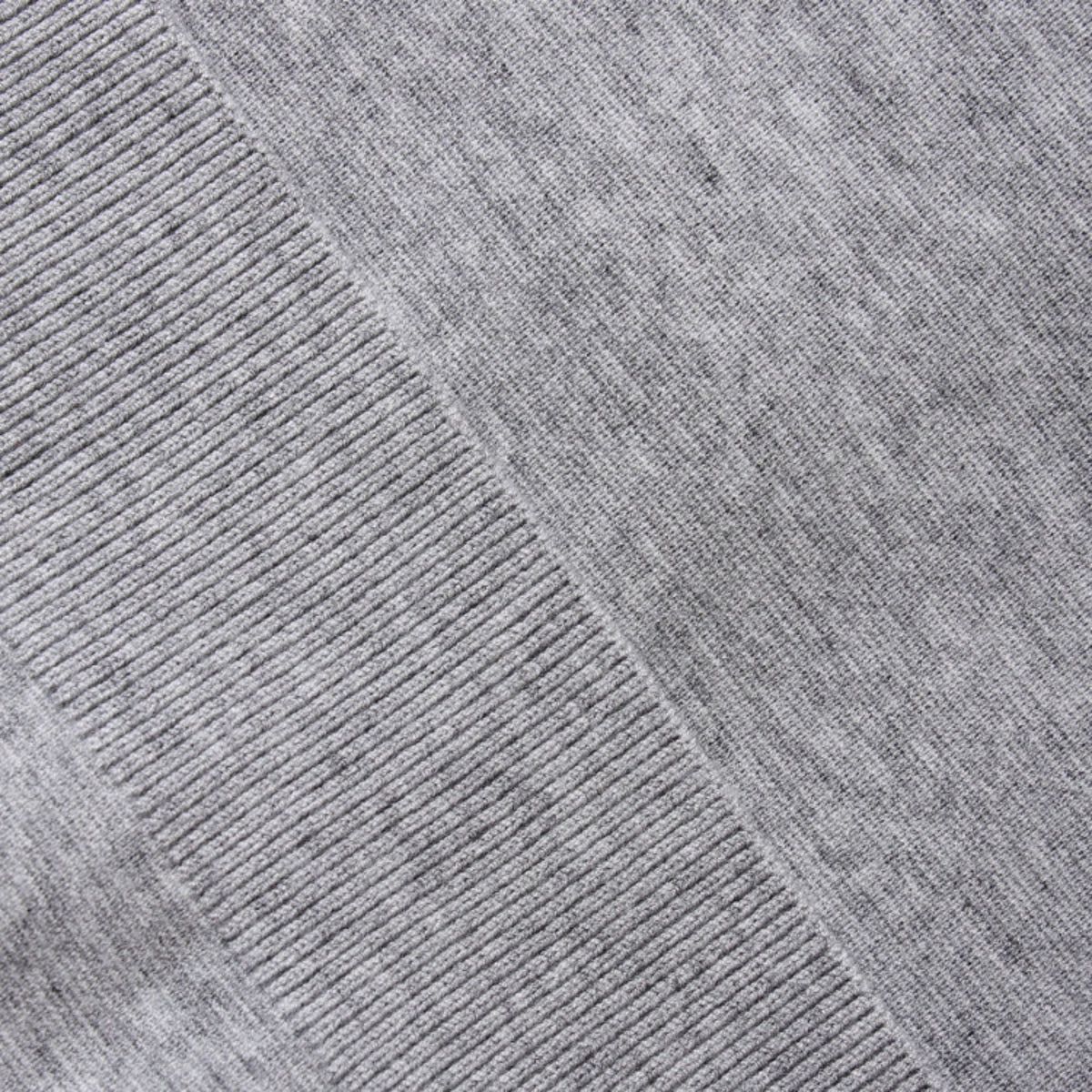 Close-up of a heather gray knit fabric with a diagonal ribbed seam, showing the texture and weave detail.