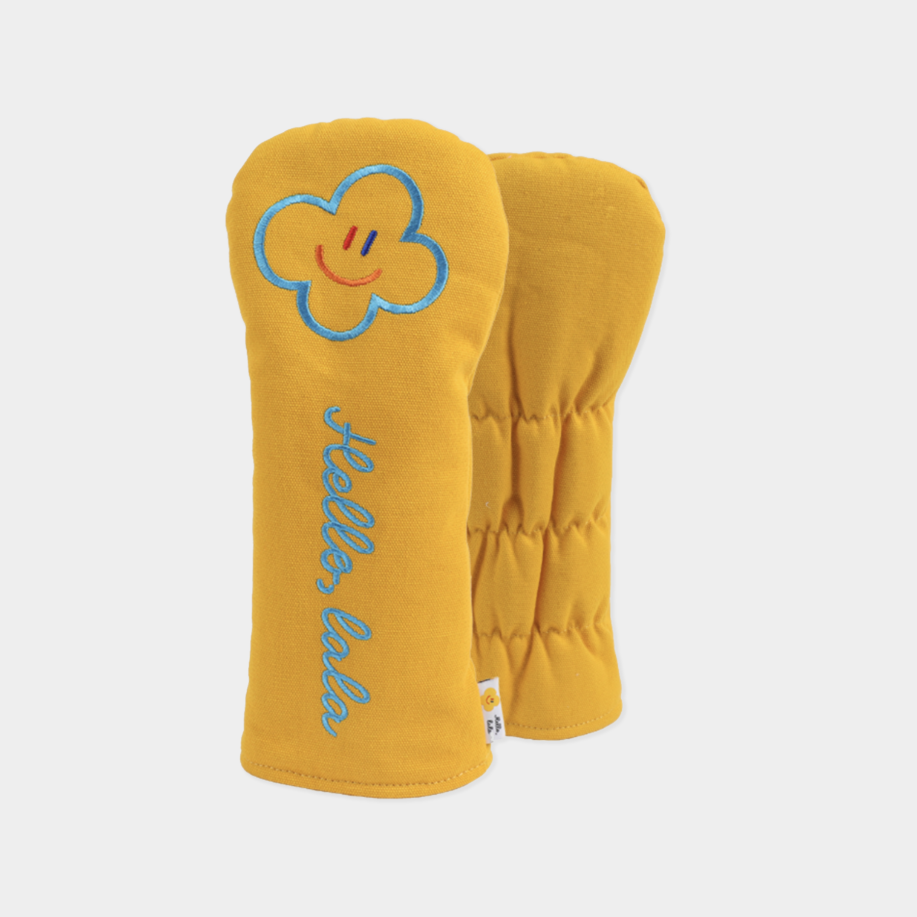 A pair of mustard yellow quilted baby headcover with embroidered details, including a smiling cloud on one bootie and the words 'Hello, baby' in blue script.