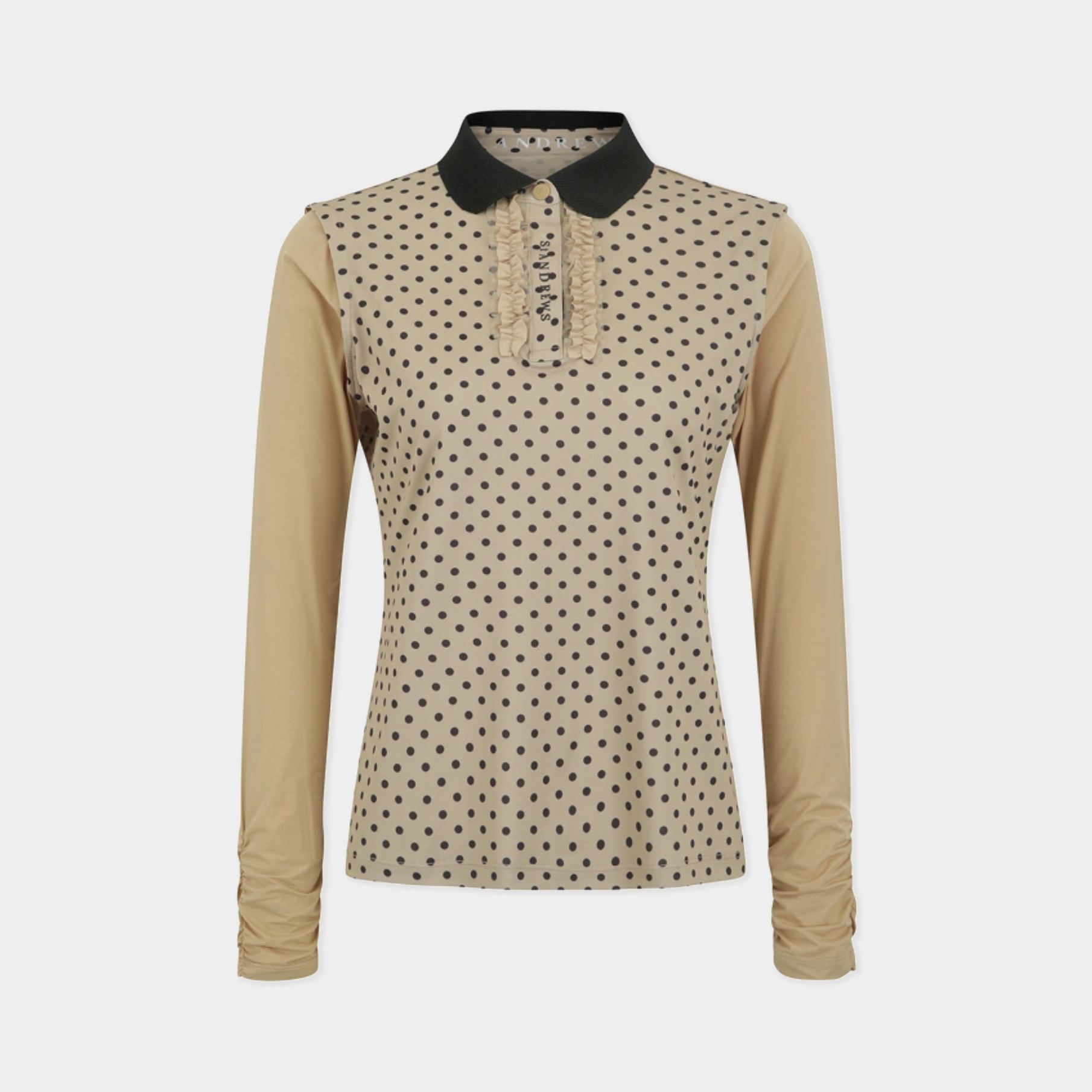 A women's long-sleeve polo shirt in beige with a black polka dot pattern on the front panel, a solid beige sleeve, and a contrasting black collar.