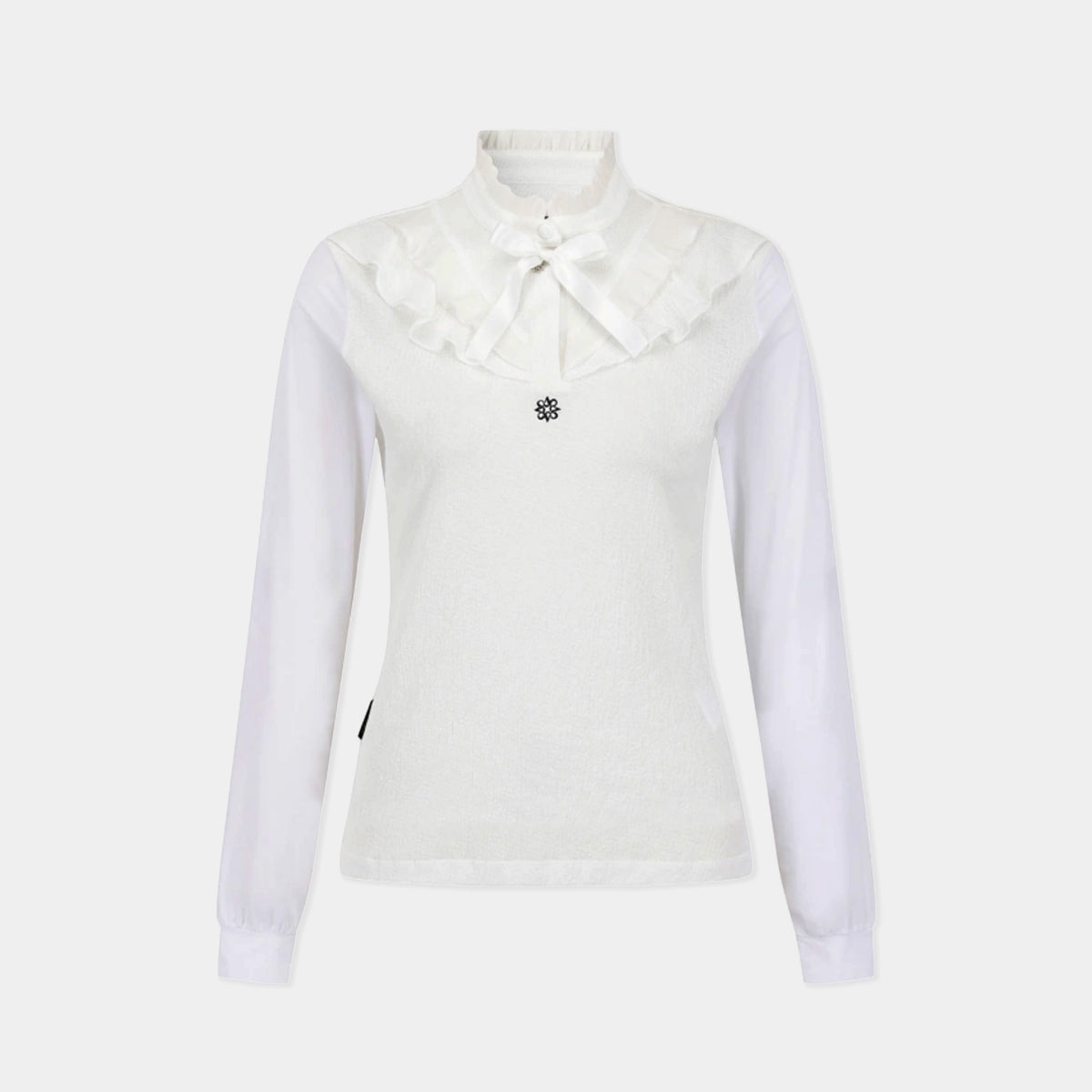 A white long-sleeve knit top featuring a layered ruffled collar with a matching fabric bow at the neck, and a small black floral embellishment on the chest, shown against a light gray background.