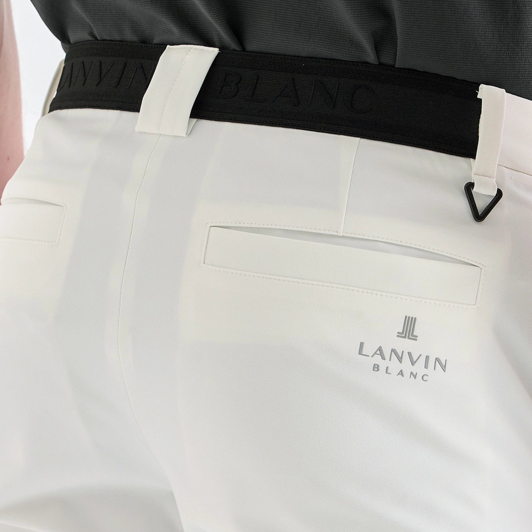 Close-up of white Lanvin Blanc trousers with a black waistband and the Lanvin Blanc logo on the back pocket.