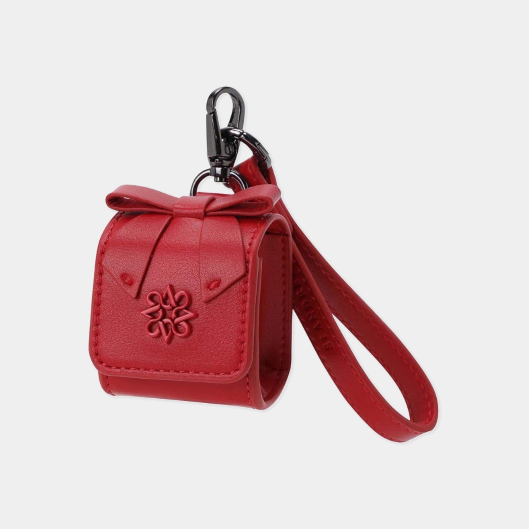 A red faux leather keychain pouch with a matching wrist strap and black metal carabiner, featuring an embossed floral design on the front, set against a light gray background.