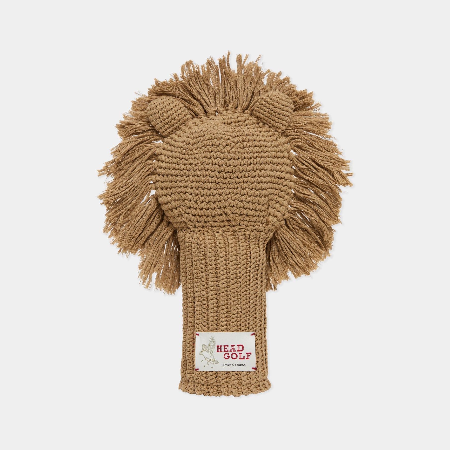 A tan knit golf headcover designed to look like a lion's face, featuring a textured body and a fluffy mane, with a visible 'HEAD GOLF' brand label on the neck, set against a plain light gray background.