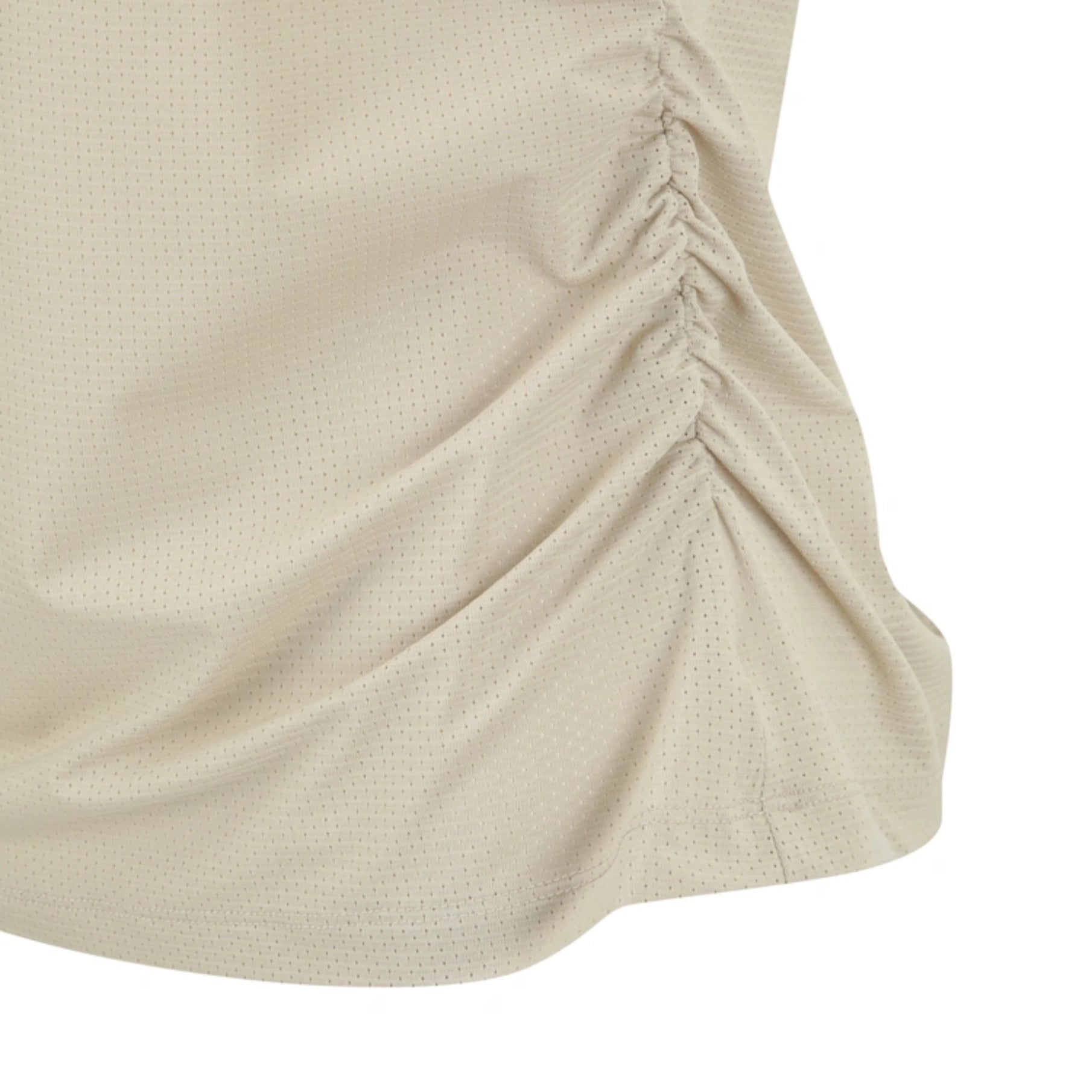 Close-up of a beige textured athletic top with a ruched side seam, showing the fabric's fine mesh-like pattern against a white background.