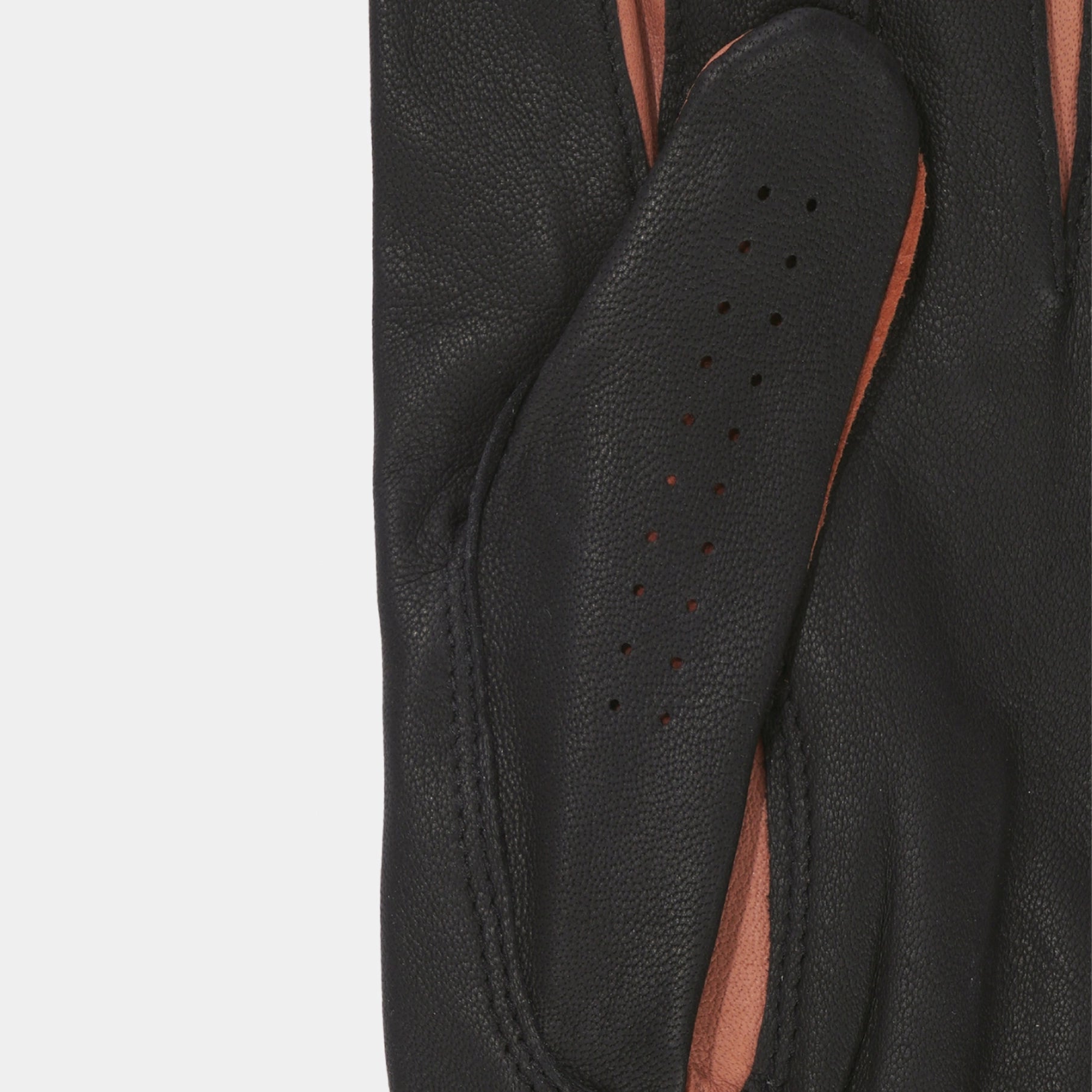 Close-up of a black leather glove showing the textured palm side with perforations, revealing a contrasting warm brown lining.