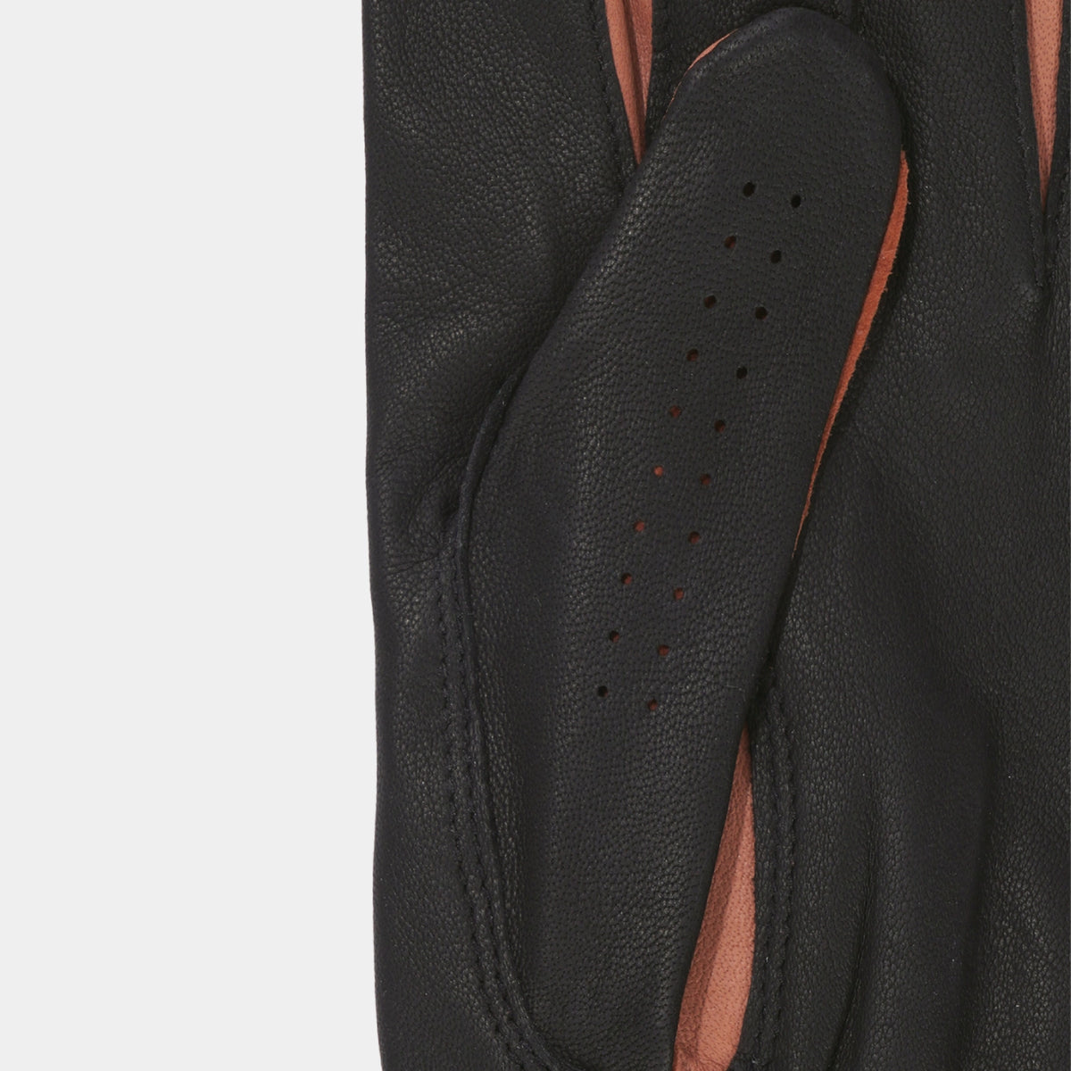 Close-up of a black leather glove showing the textured palm side with perforations, revealing a contrasting warm brown lining.