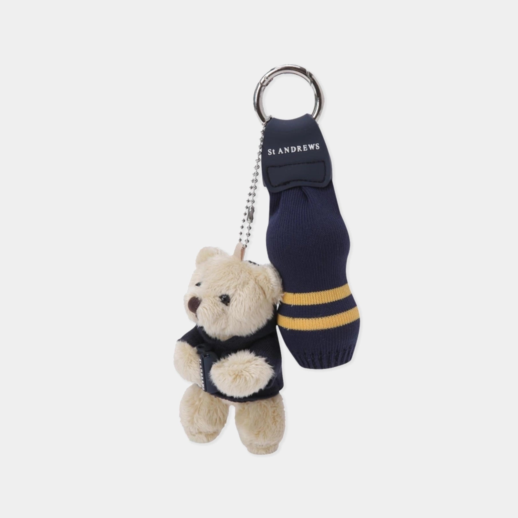 A St Andrews collegiate-themed keychain featuring a plush teddy bear in a navy sweater next to a miniature navy sock with yellow stripes and a metal split ring.