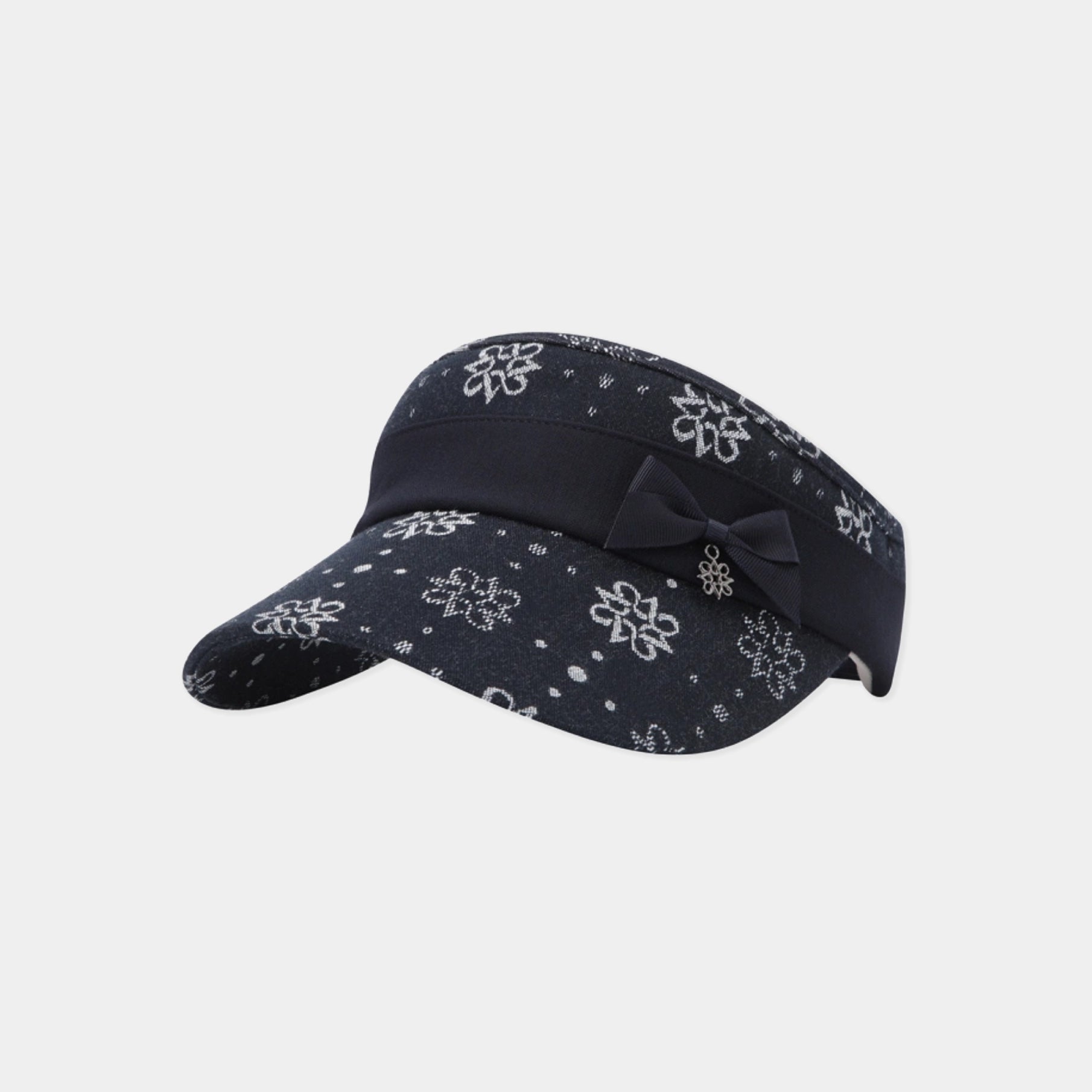 A dark navy blue visor hat featuring a white snowflake and dot pattern, accented with a matching fabric bow on the front, set against a plain light gray background.