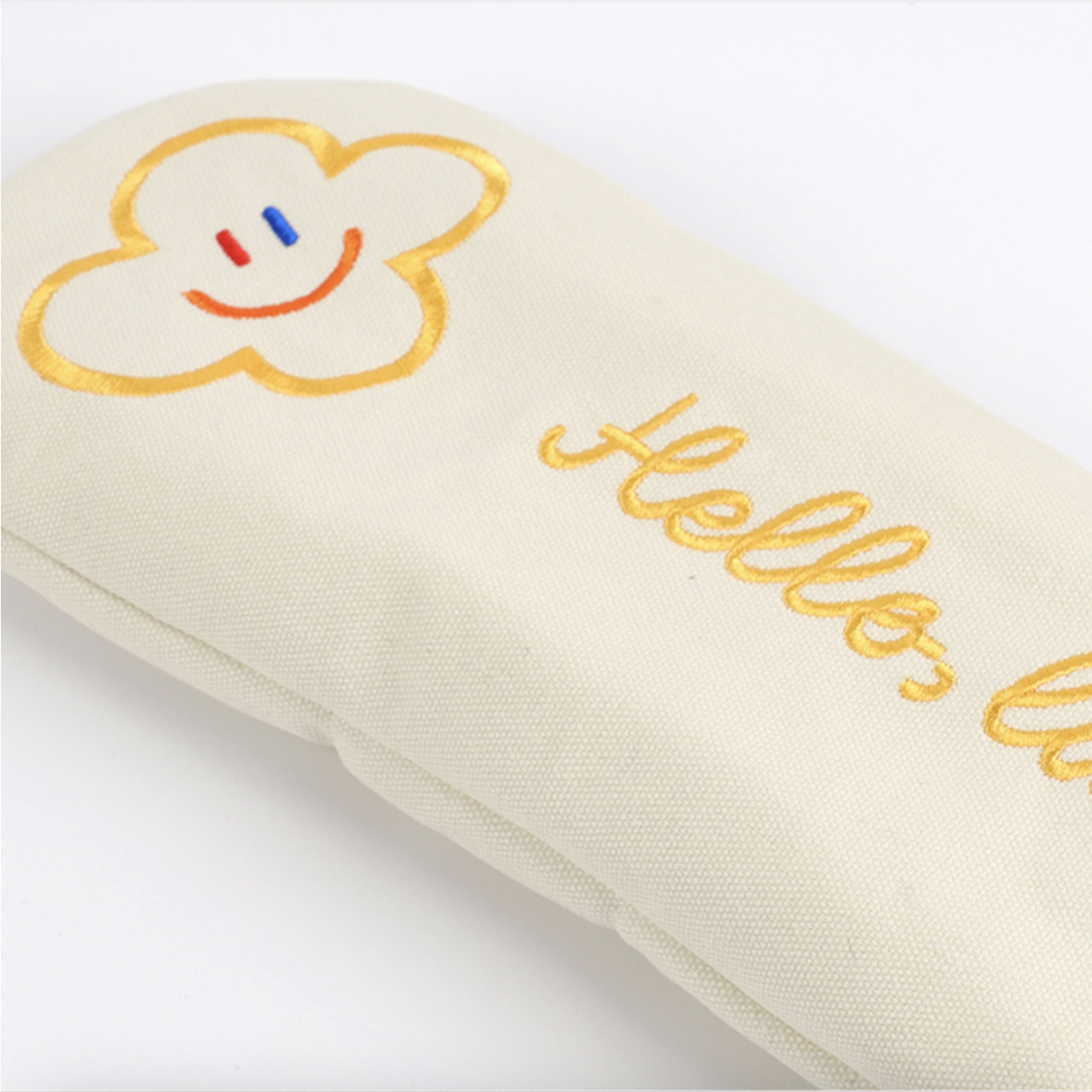 An off-white fabric headcover with gold embroidered text reading 'Hello, ' and a gold cloud outline containing a small smiley face with blue and red details, shown on a white background.