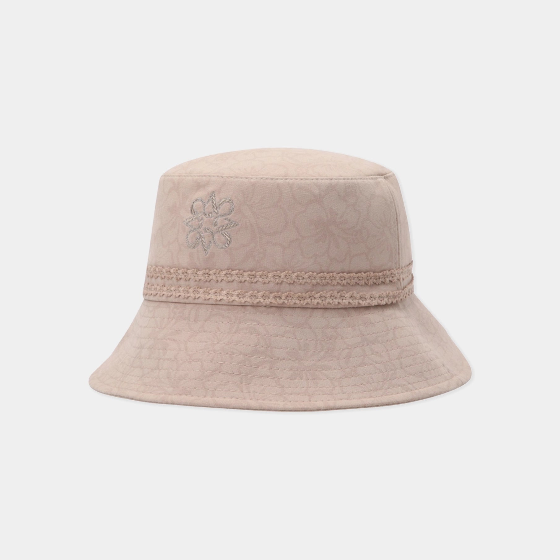 A light beige bucket hat with a subtle floral pattern, a decorative braided band, and a small embroidered flower on the side, shown against a plain light gray background.