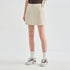 A model wearing a light beige athletic mini skirt, paired with white crew socks and white sneakers with dark accents, shown from the waist down against a light gray studio background.