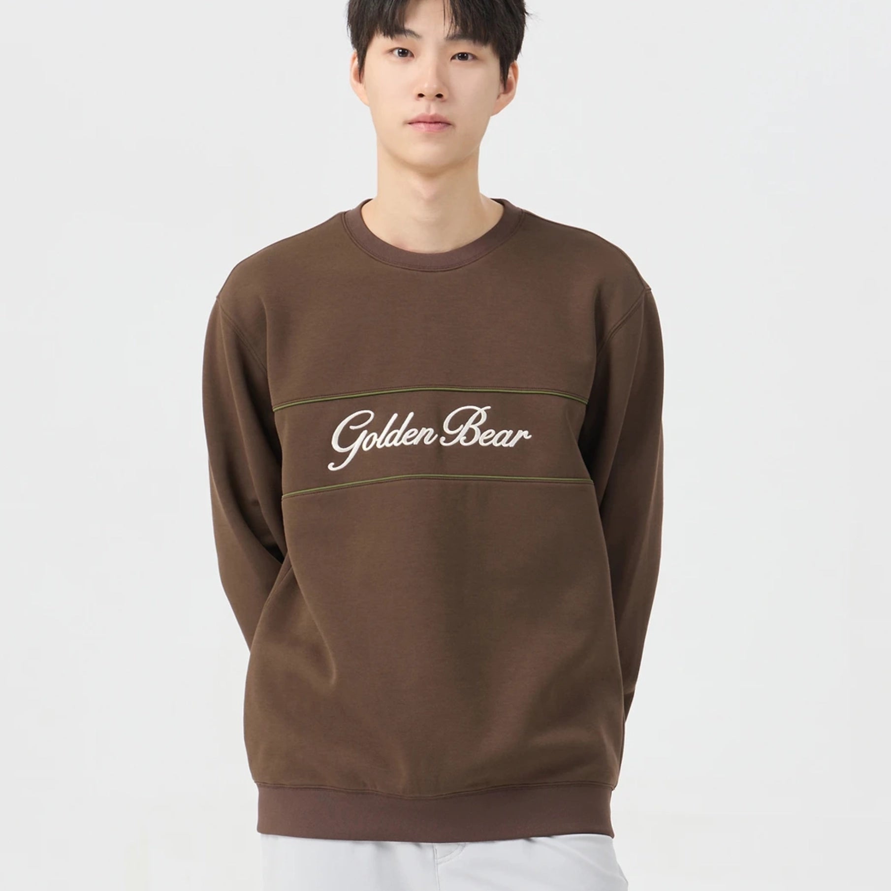 A man wearing a brown crewneck sweatshirt with 'Golden Bear' embroidered in white script across the chest, set against a plain light gray background.
