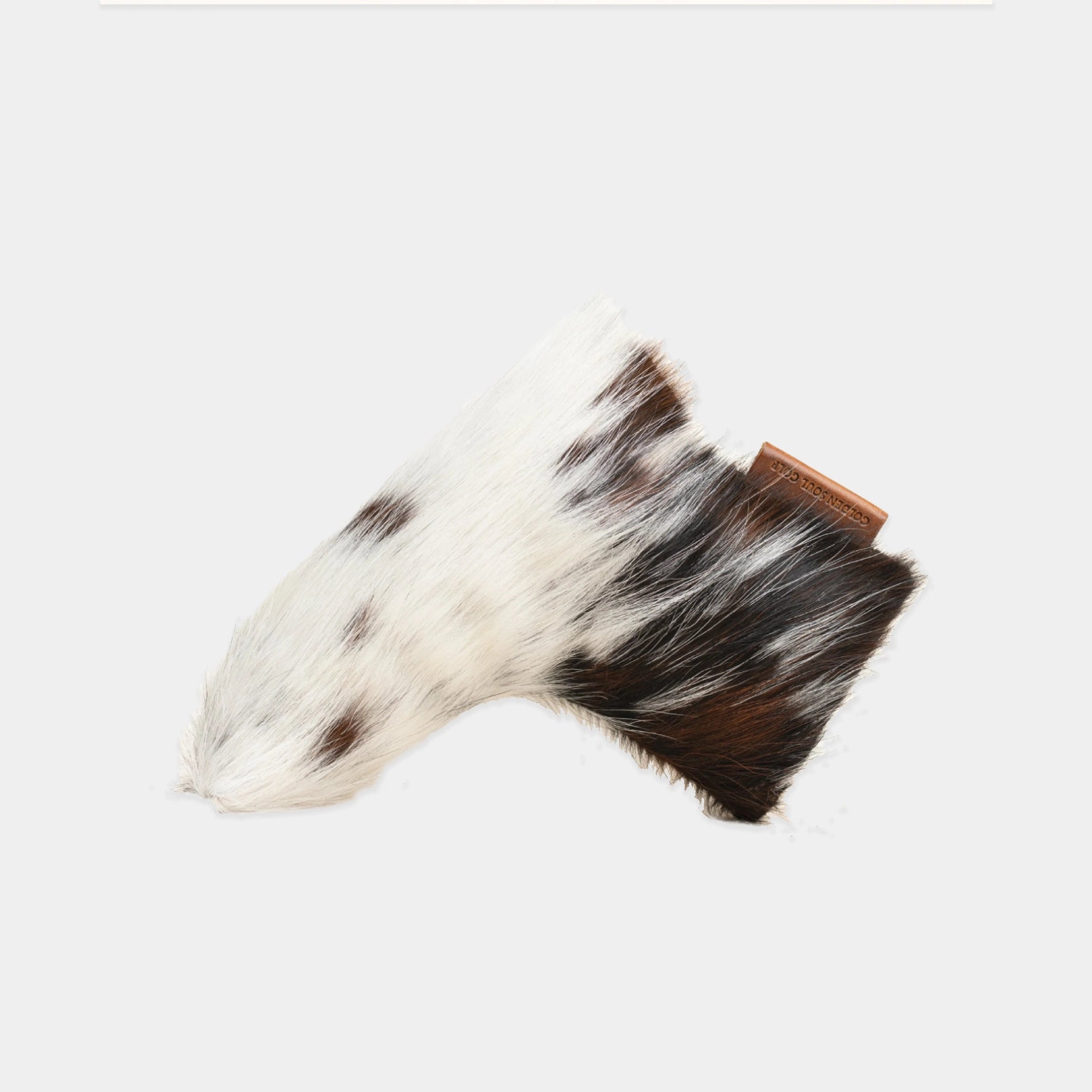 A putter cover from a cowhide tail, featuring a white and black spotted pattern with a dark brown base, shown on a light gray background.