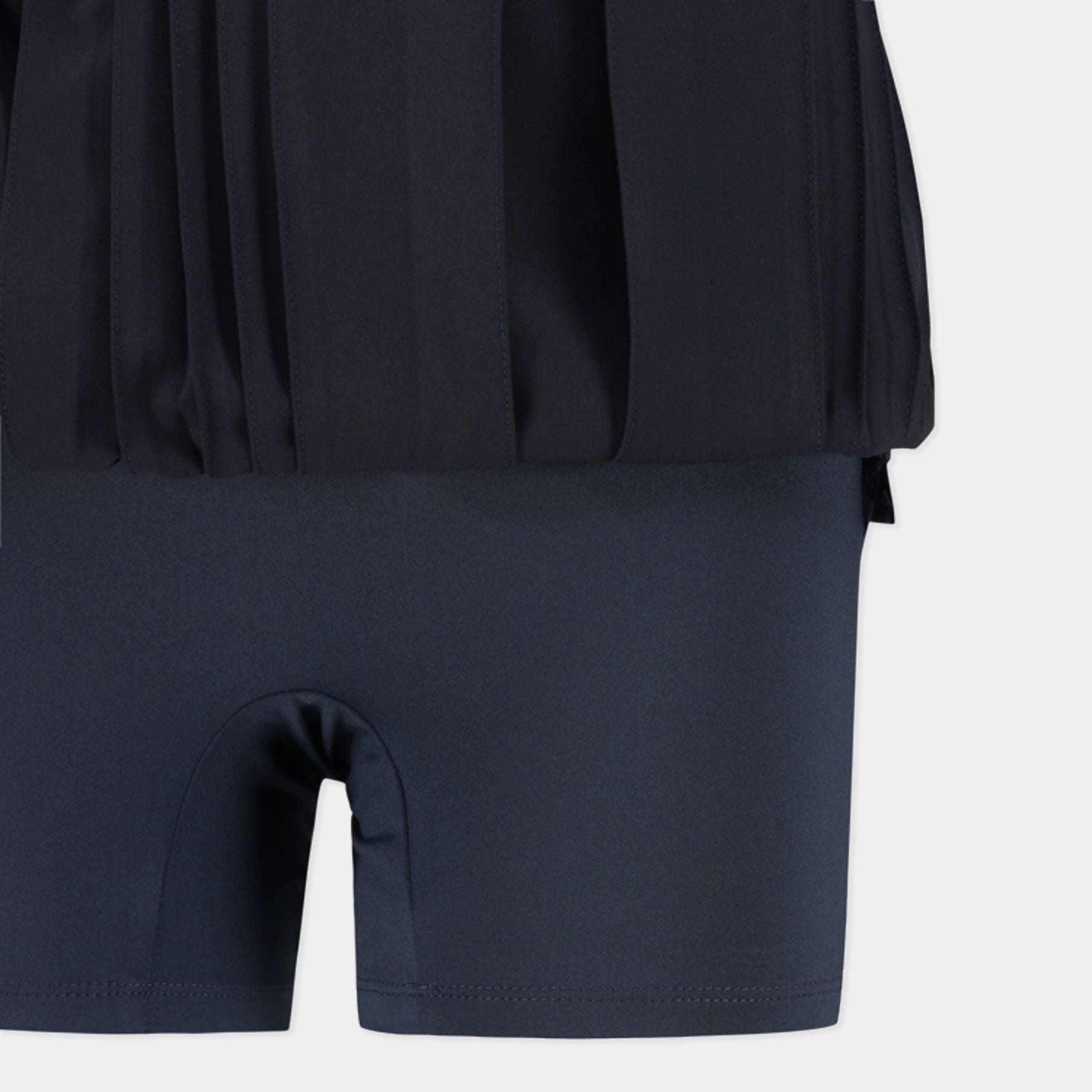 Close-up of a dark navy athletic outfit showing a pleated black top and matching high-waisted shorts with a built-in pouch.