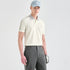 A male model wearing a light cream-colored short-sleeve polo shirt with gray accents on the collar and shoulders, paired with gray trousers, a light blue cap, and a golf glove, set against a plain light gray studio background.