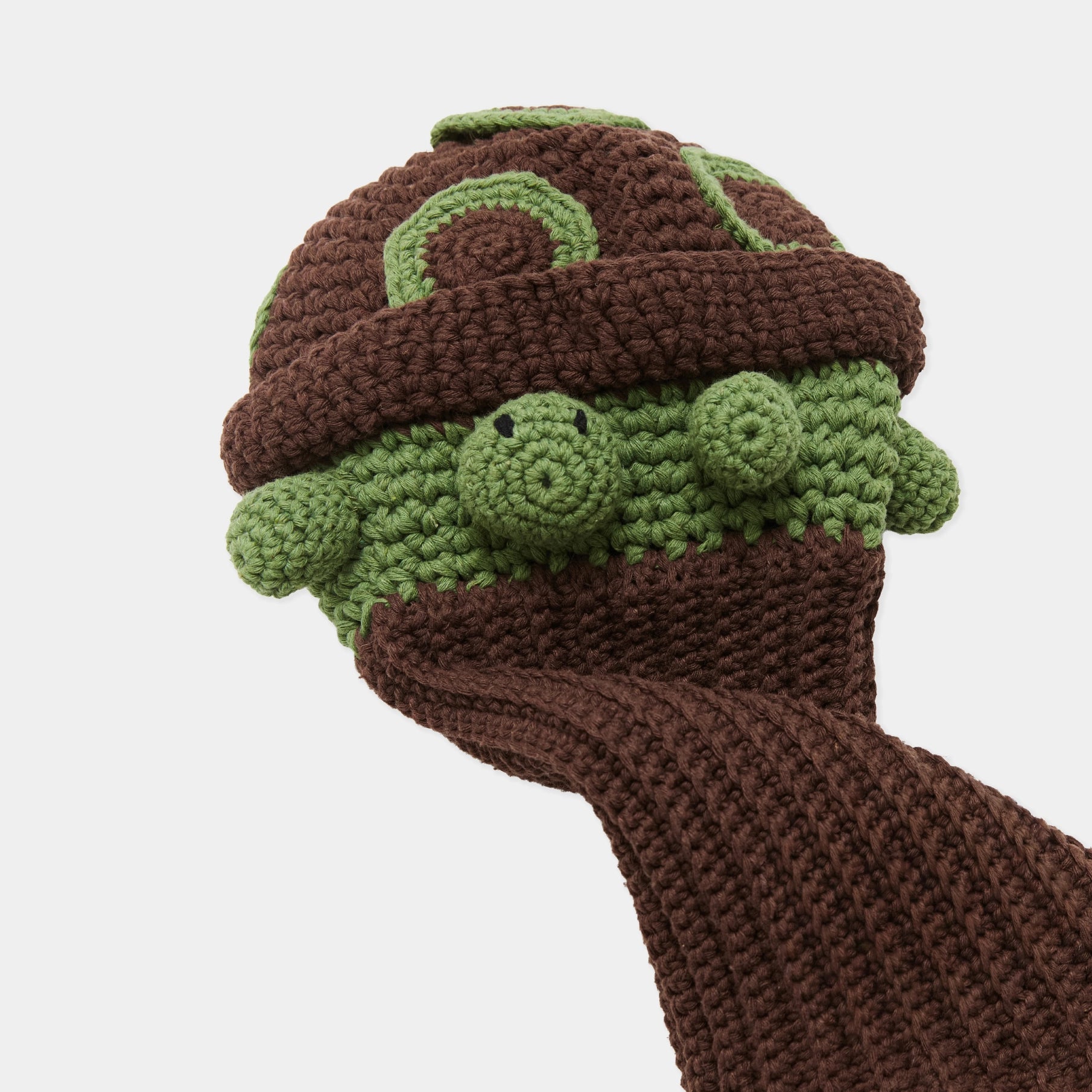 A crocheted turtle-shaped golf head cover with a brown knit body and cap, green textured shell and head, and a matching brown cuff, shown on a light gray background.