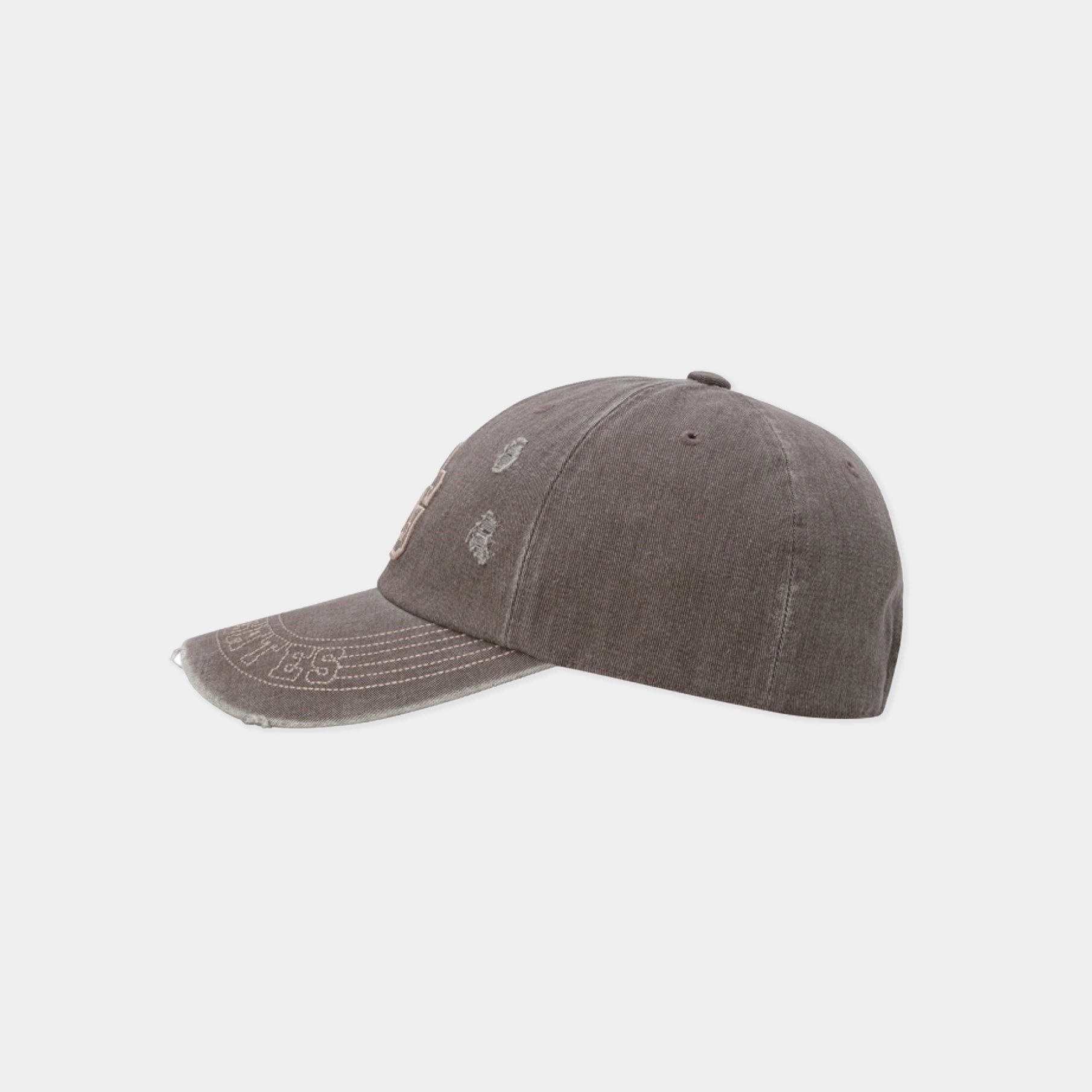 A washed dark gray baseball cap with distressed details and tonal embroidery, shown from a side profile on a light gray background.