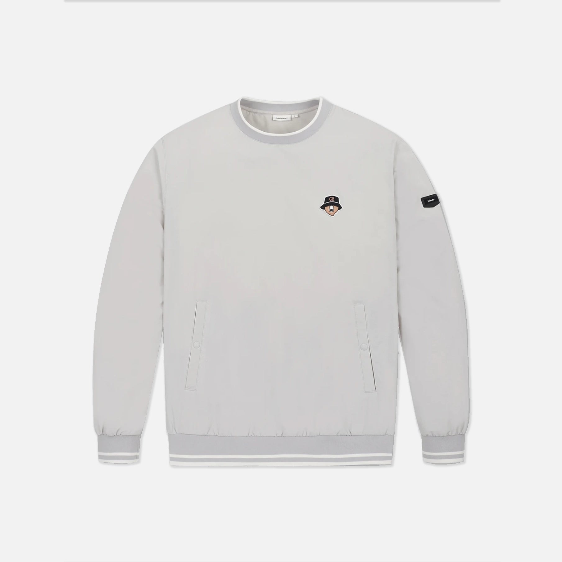 A light gray crewneck sweatshirt with a small embroidered character patch on the left chest and a black brand patch on the right sleeve, displayed on a clean light gray background.