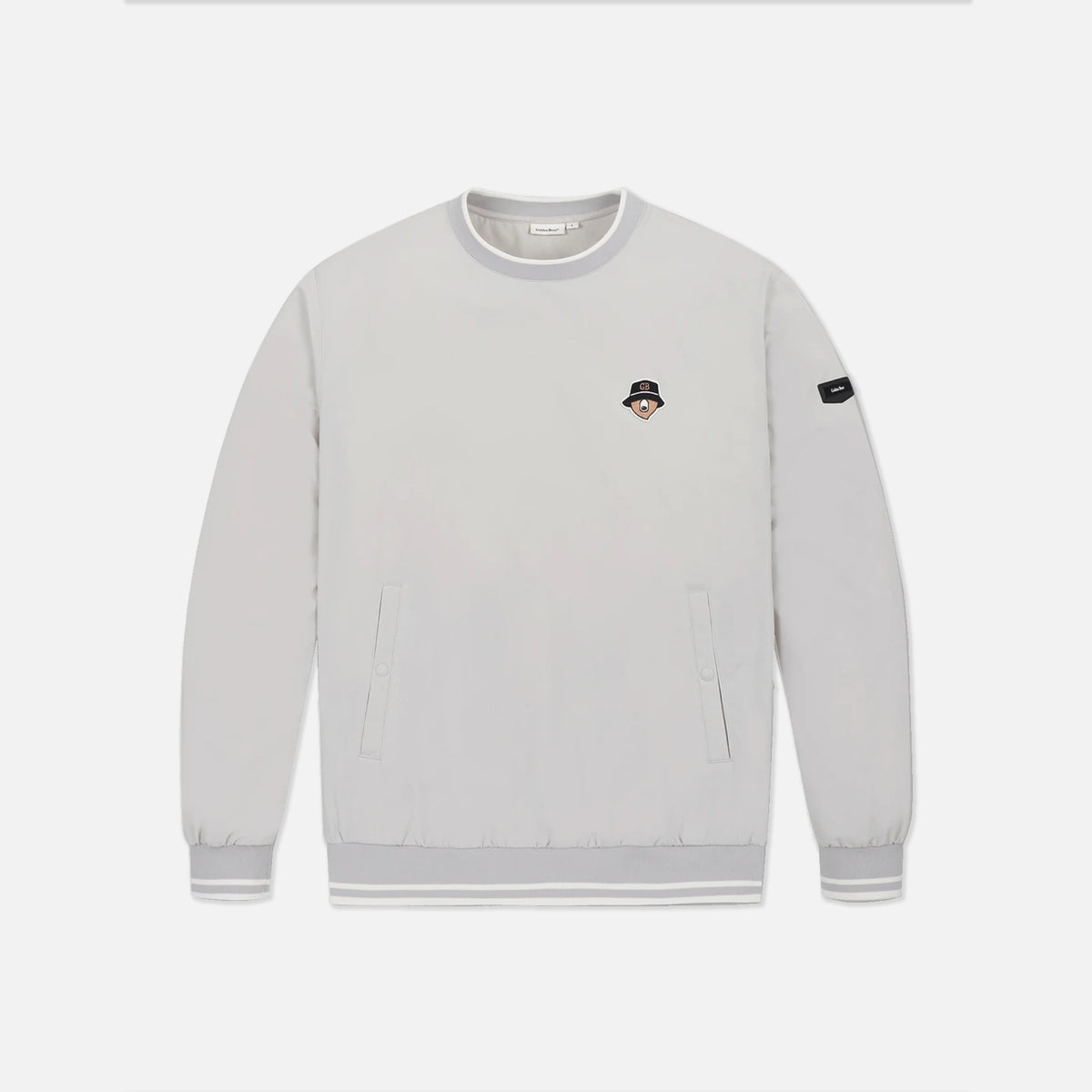 A light gray crewneck sweatshirt with a small embroidered character patch on the left chest and a black brand patch on the right sleeve, displayed on a clean light gray background.
