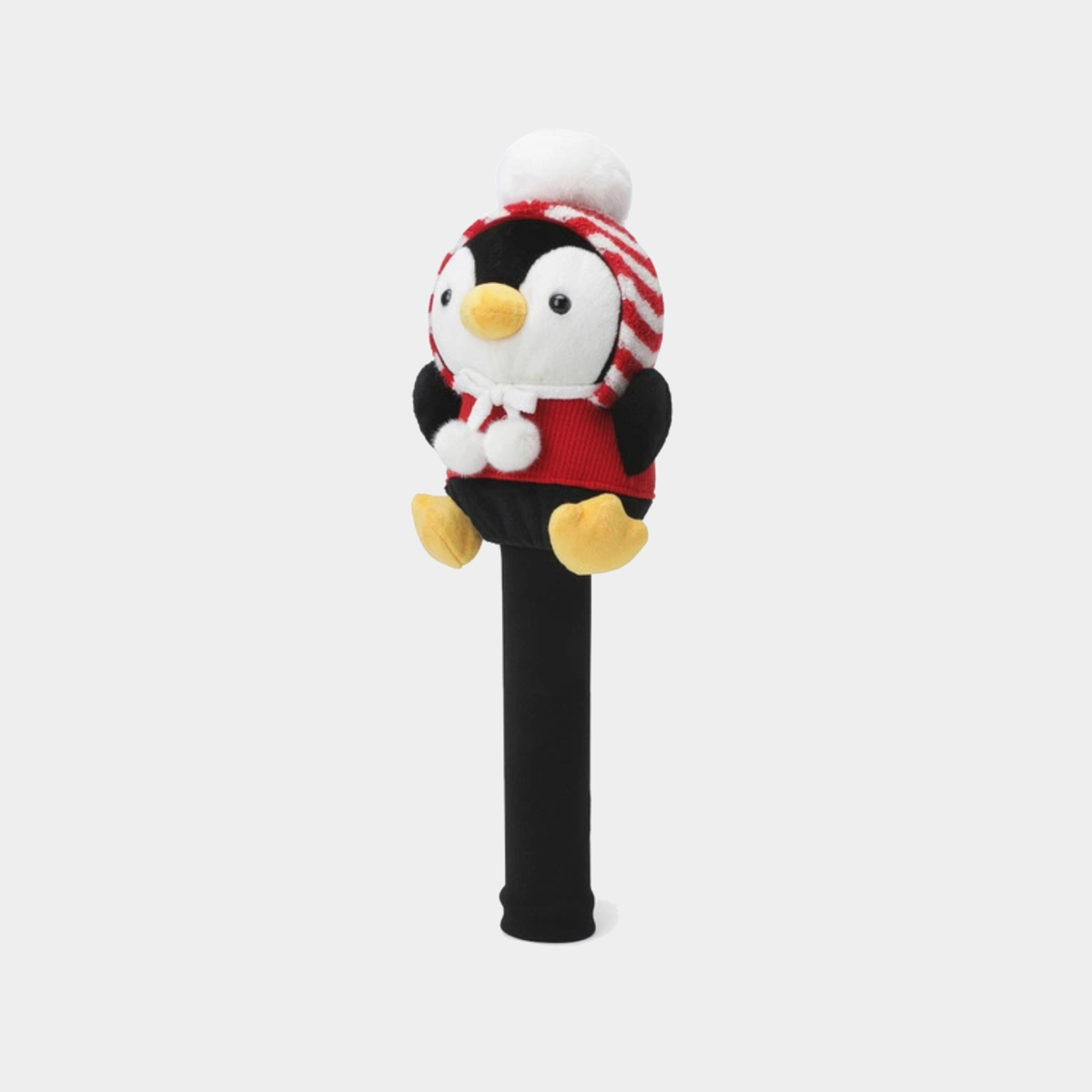 A plush penguin golf club headcover on a black shaft, featuring a white and red striped knit hat with a white pom-pom, a red sweater, and yellow feet, set against a light gray background.