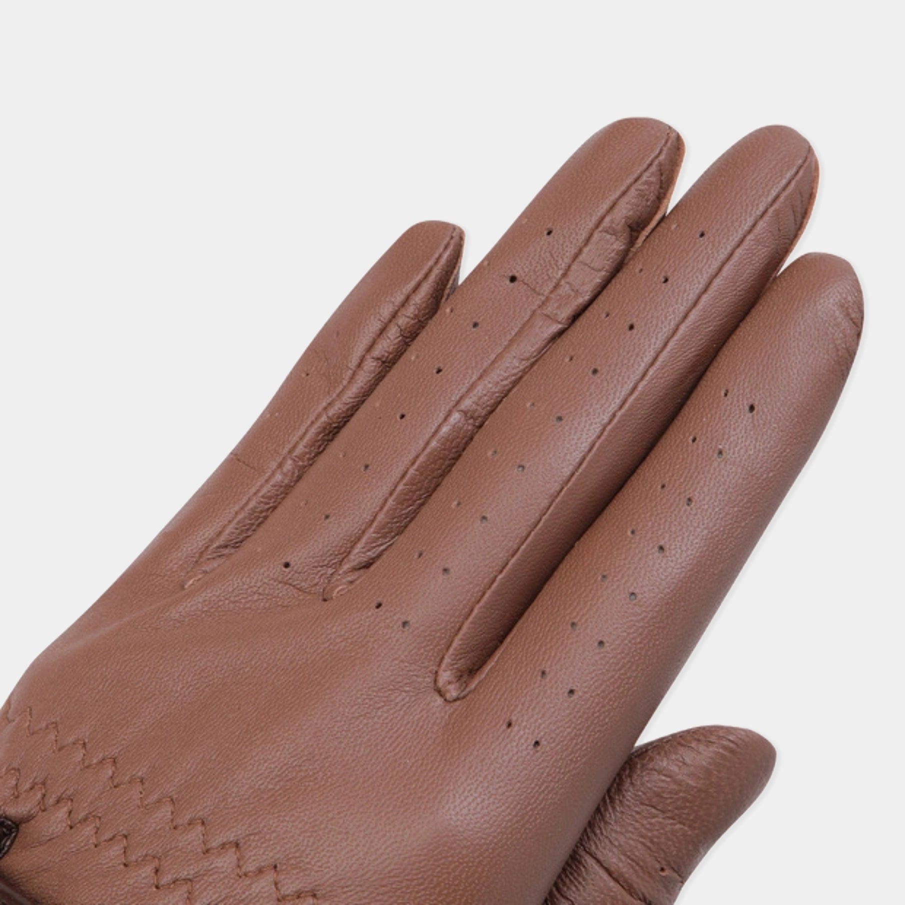 A close-up of a brown leather glove with perforated details on the fingers, shown against a light gray background.
