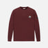 A long-sleeve crewneck shirt in maroon, featuring a small embroidered shield logo on the left chest and a black brand tag on the right sleeve, displayed against a light gray background.