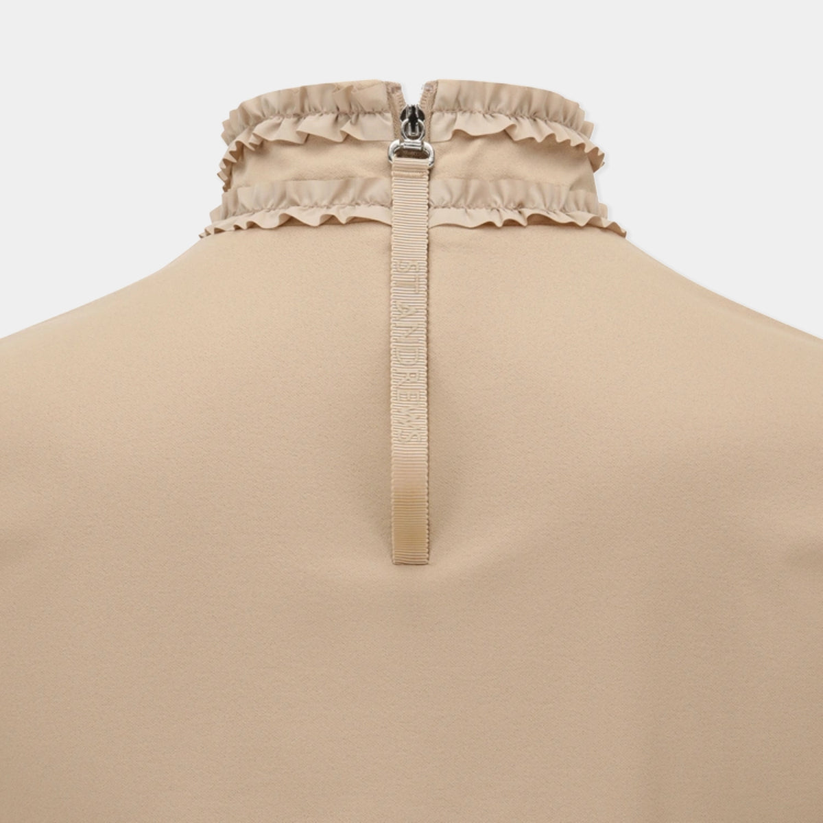 Close-up back view of a beige garment with a ruffled collar, a central zipper, and a vertical zipper pull tab on a plain light background.