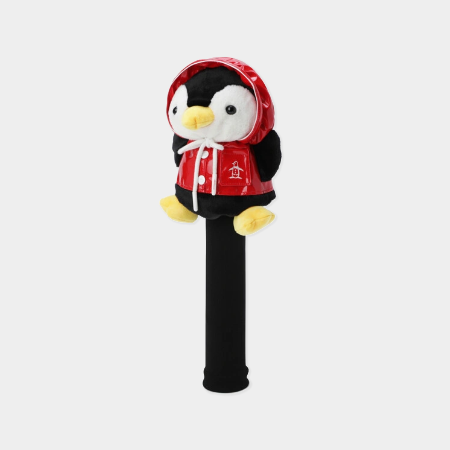 A plush penguin dressed in a red hooded jacket with white trim, mounted on a black cylindrical stand against a light gray background.